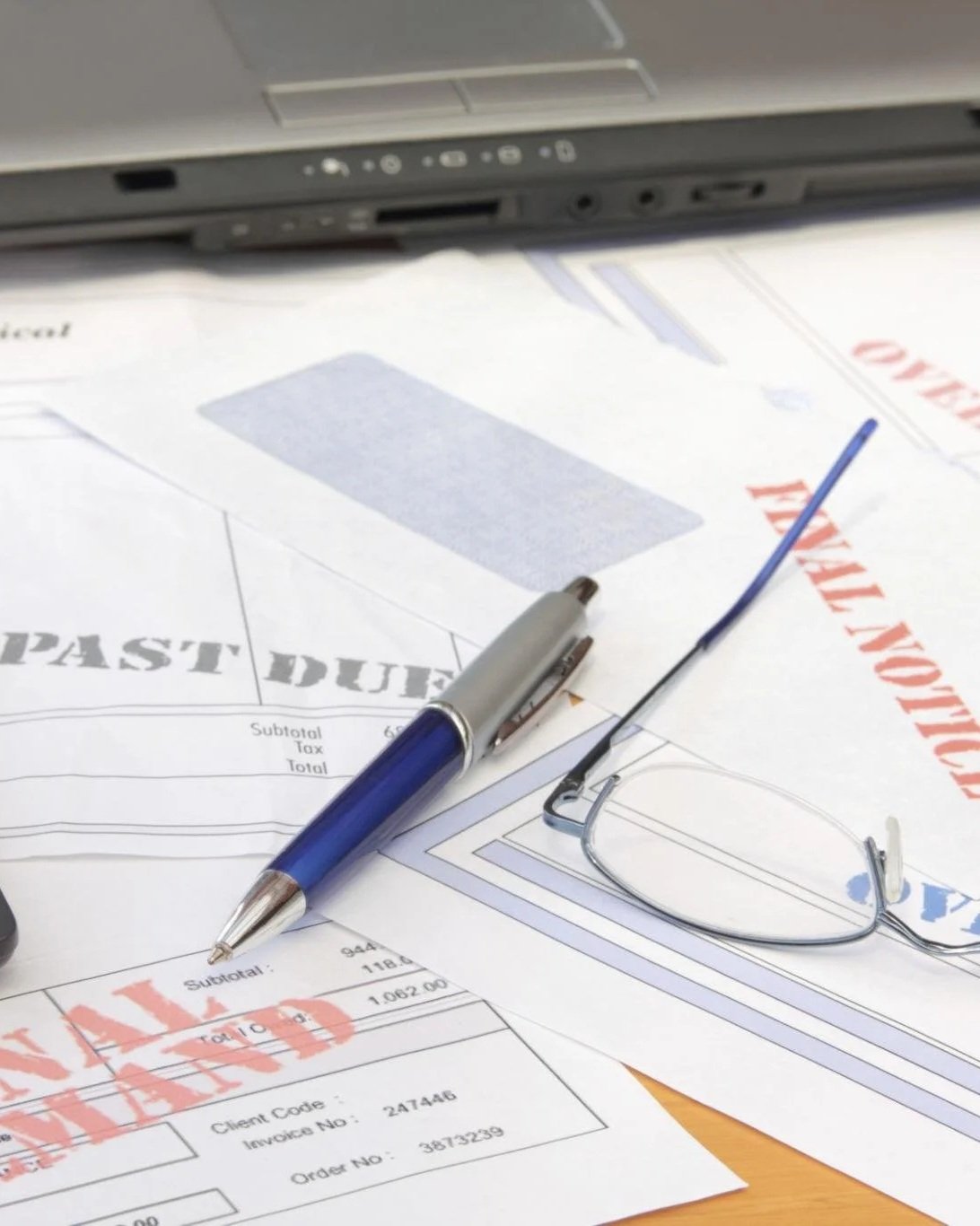 Past due and final notice business invoices on a desk with calculator showing cash flow problems for a small business in Iredell County North Carolina
