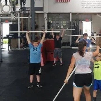 People lifting poles during a fitness class in a gym.