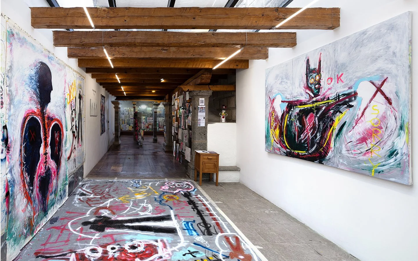 Installation view of “Tá Brón Orm” by PIGSY at Casa Lü, Mexico City, featuring immersive corridor with large-scale figurative paintings, floor work and text-based elements