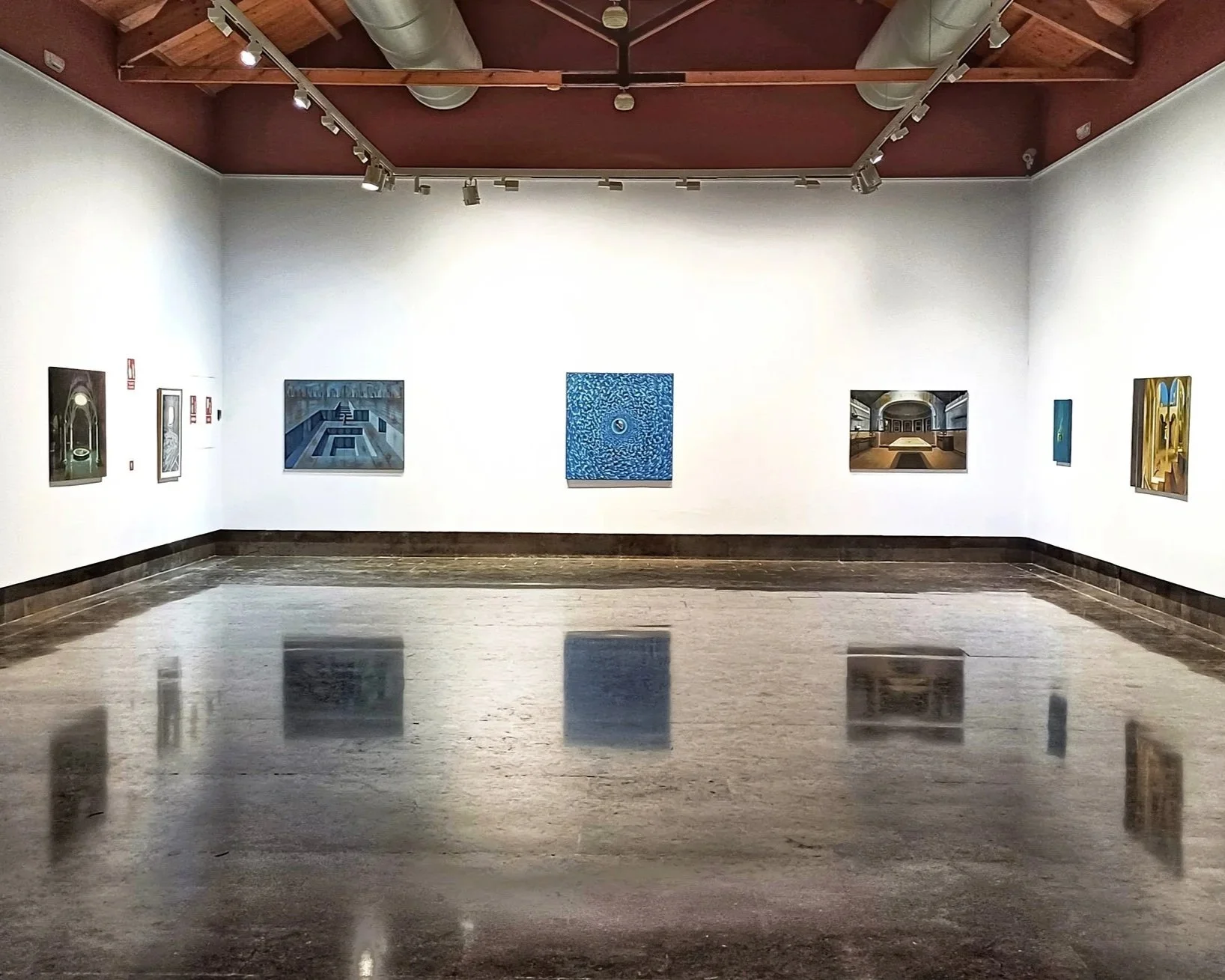 Step Stone Art art gallery with a polished floor and white walls displaying various paintings. The ceiling is wooden with exposed beams and ductwork. Overhead track lighting illuminates the artwork.