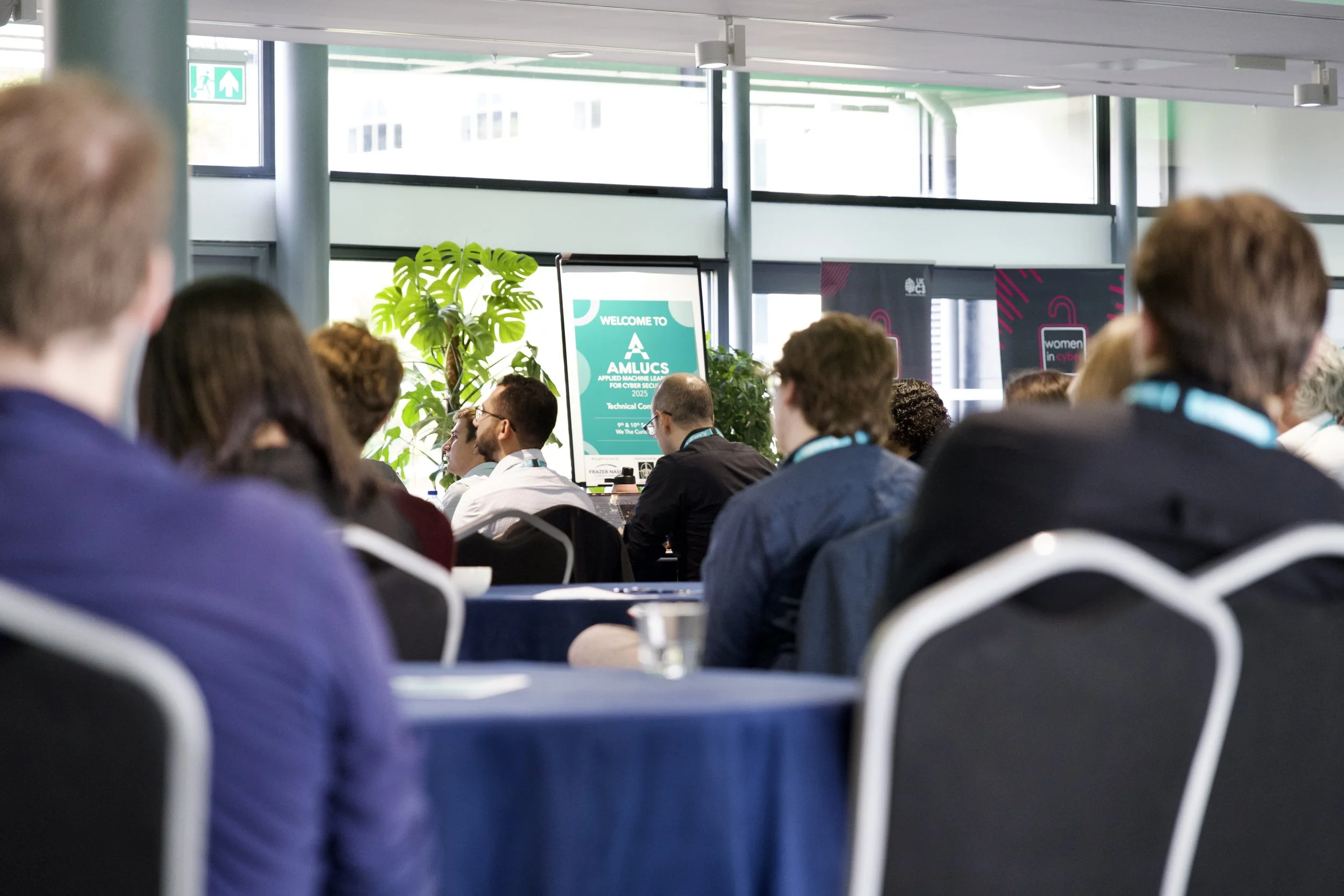 A group of people sitting in a conference or seminar room, AMLUCS 2023