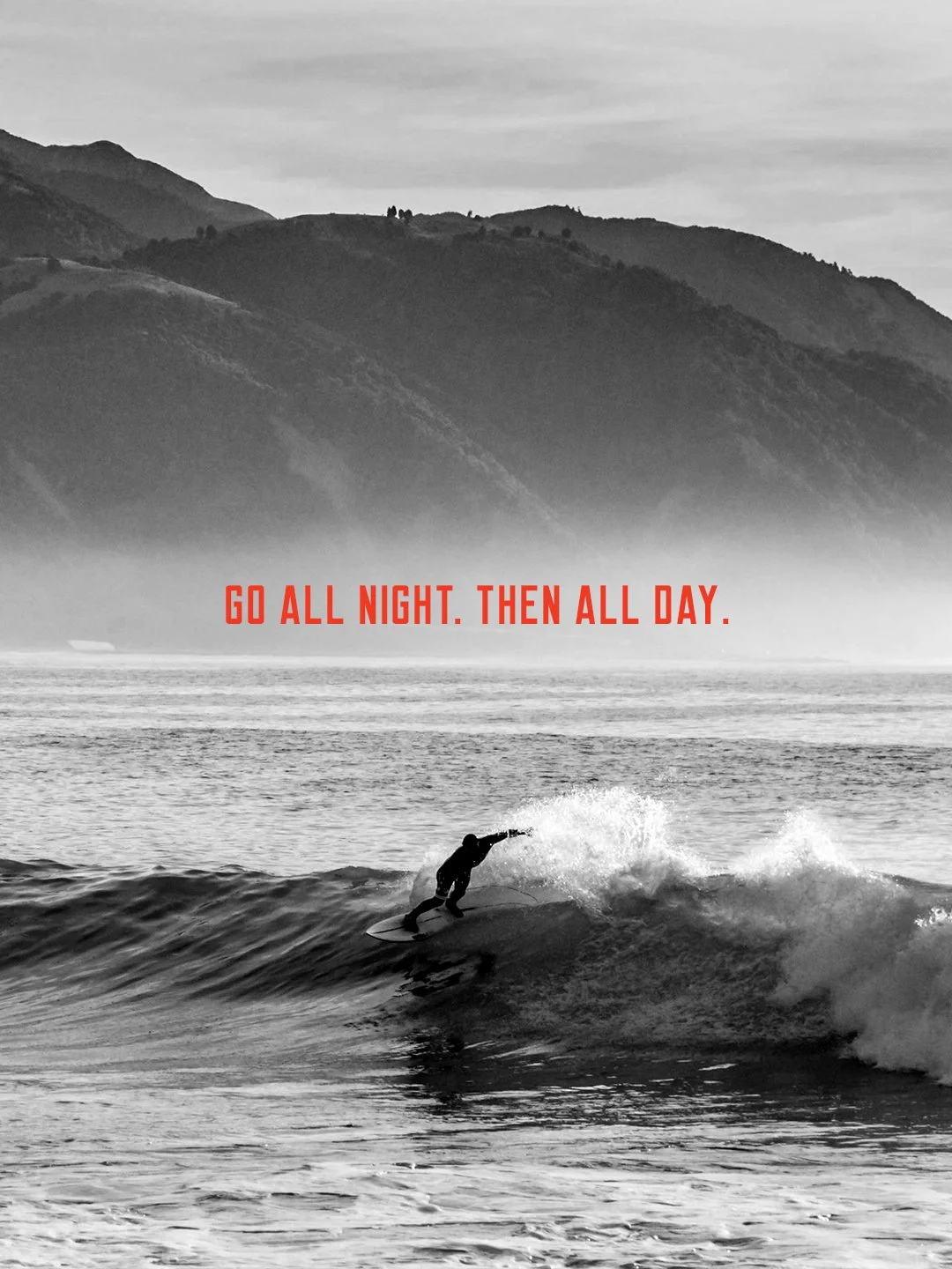 A person surfing on a wave in black and white with mountainous landscape in the background and the text 'Go all night. Then all day.' in red.