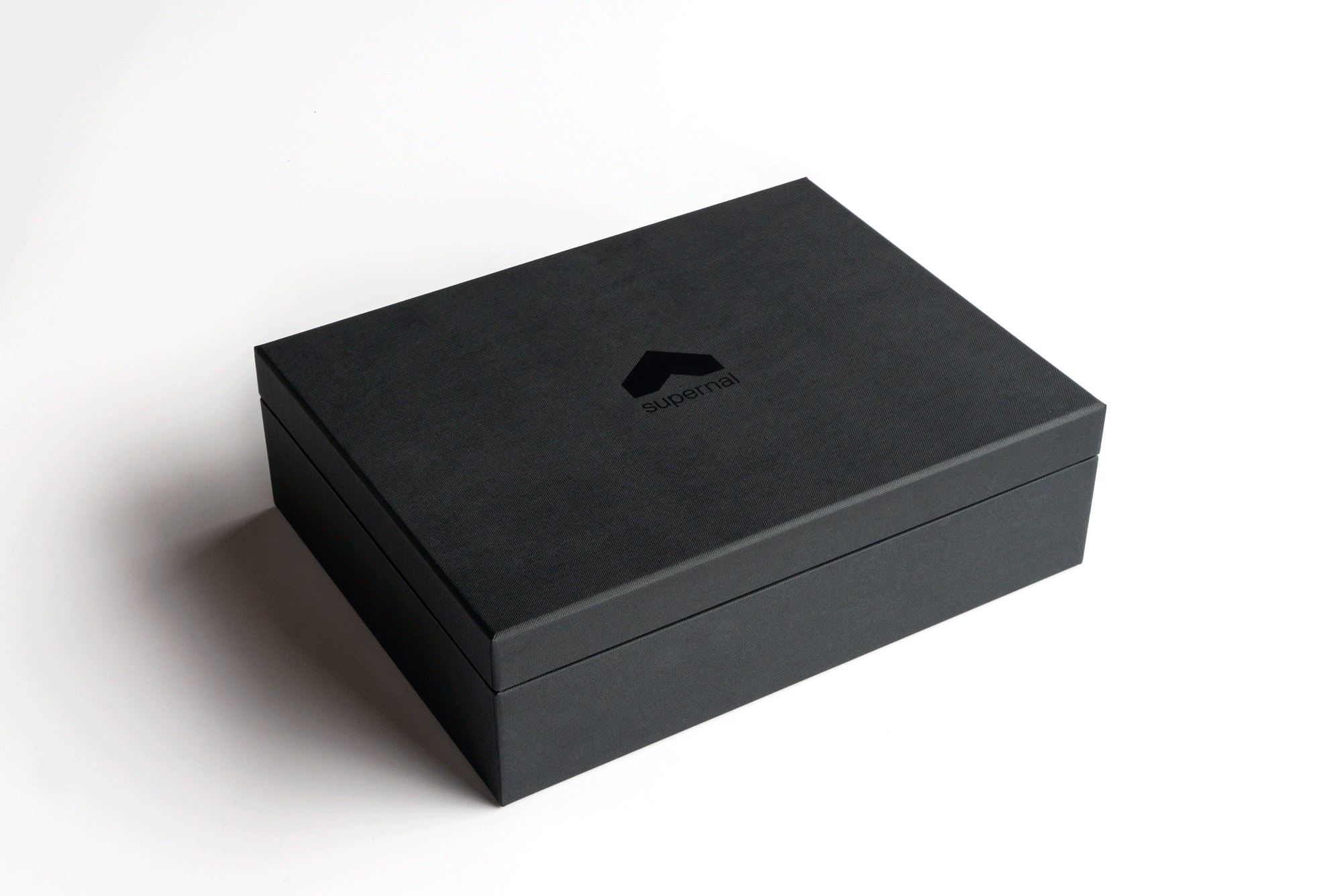 A dark gray rectangular box with the word "supernal" and a hexagonal logo printed on the top, placed on a white surface.