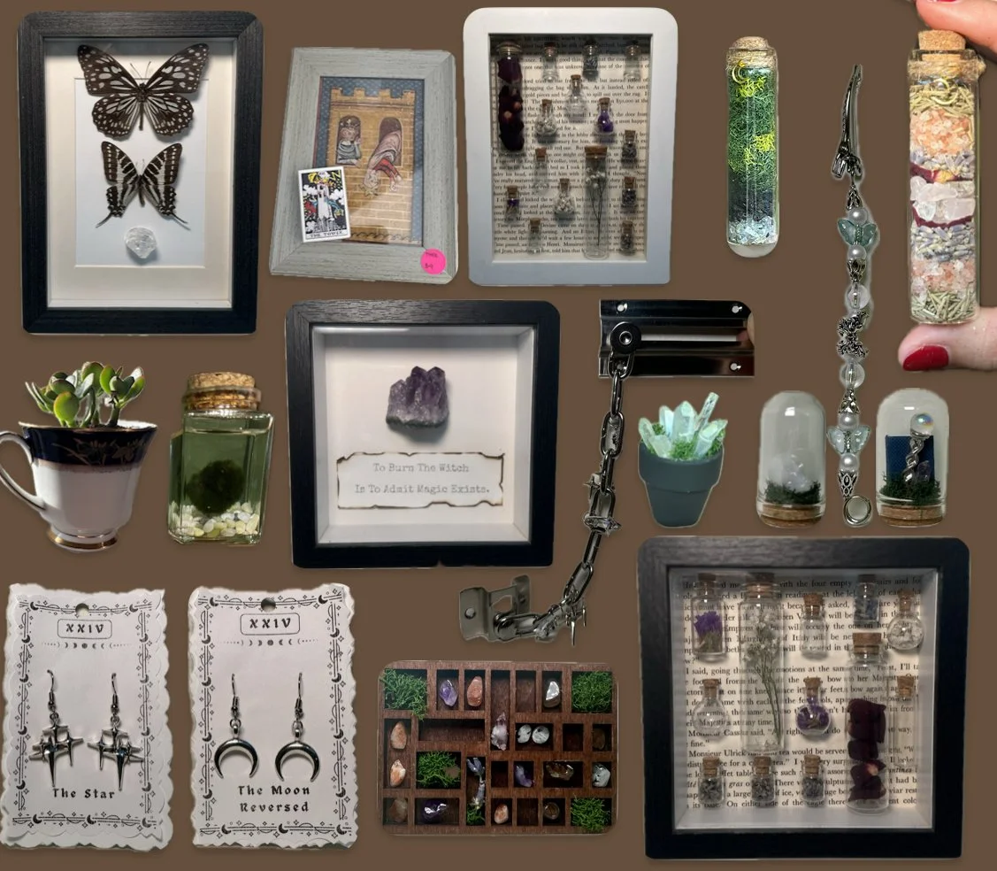 Collection of small decorative items, including framed butterflies, a photo, vials with colorful contents, a bracelet, a teacup with succulents, a jar with moss, a small amethyst and a quote, tarot cards, a ring display, crystals, and various jewelry pieces.