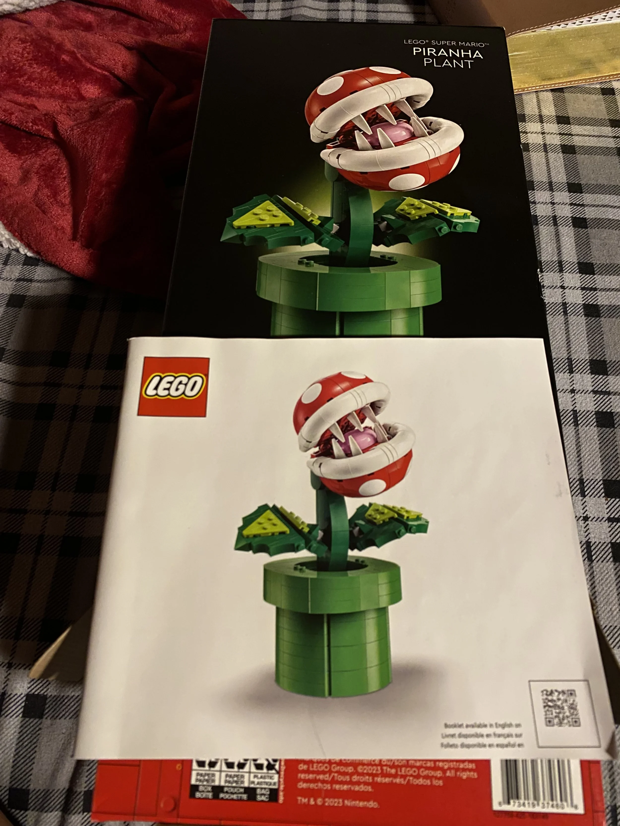 Two LEGO instruction booklets for building a Piranha Plant from Super Mario, featuring a LEGO model of the plant with a red and white spotted head, sharp teeth, and green leaves, one booklet with a dark background and the other with a white background.