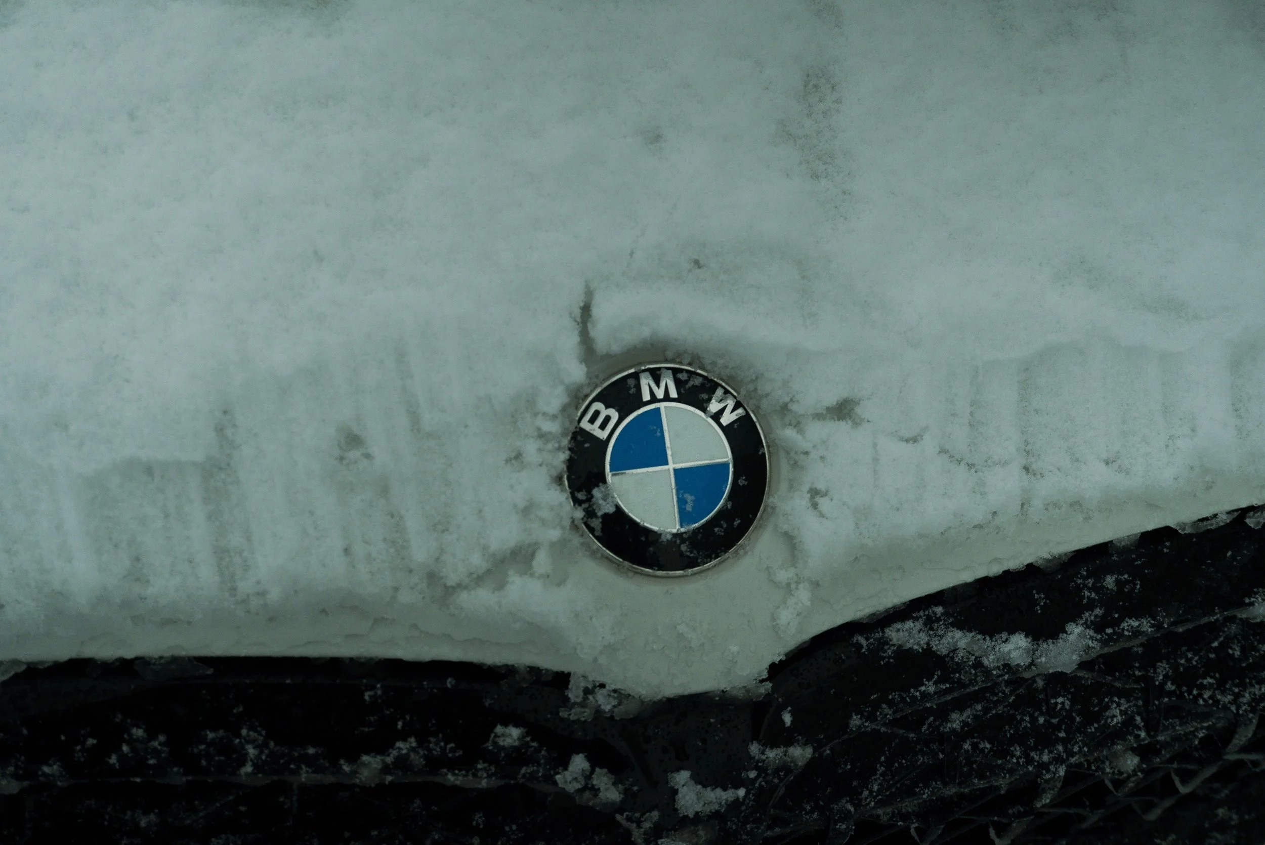 BMW logo emblem on a snow-covered car hood.