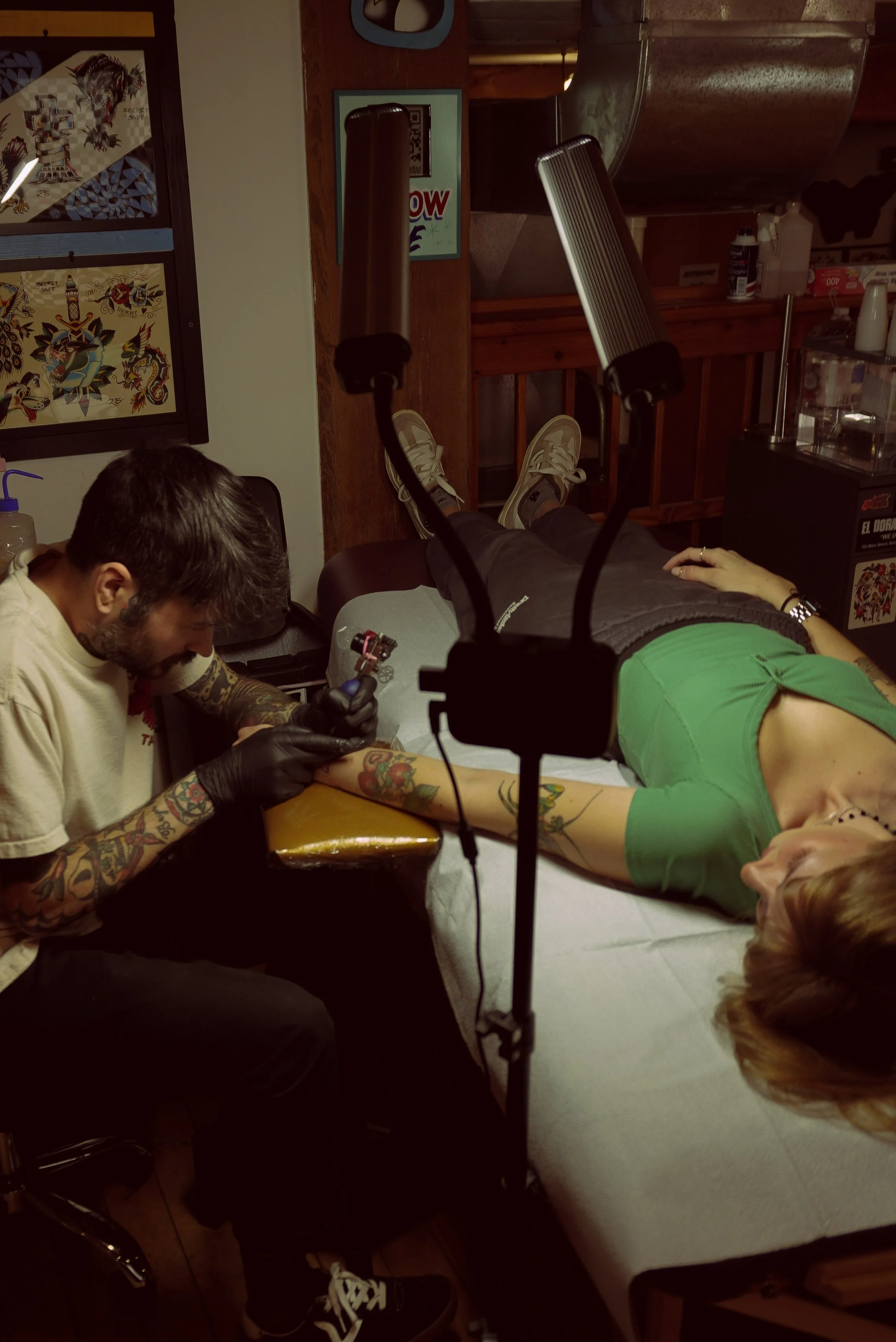 Tattoo artist tattooing a person's arm in a tattoo studio.