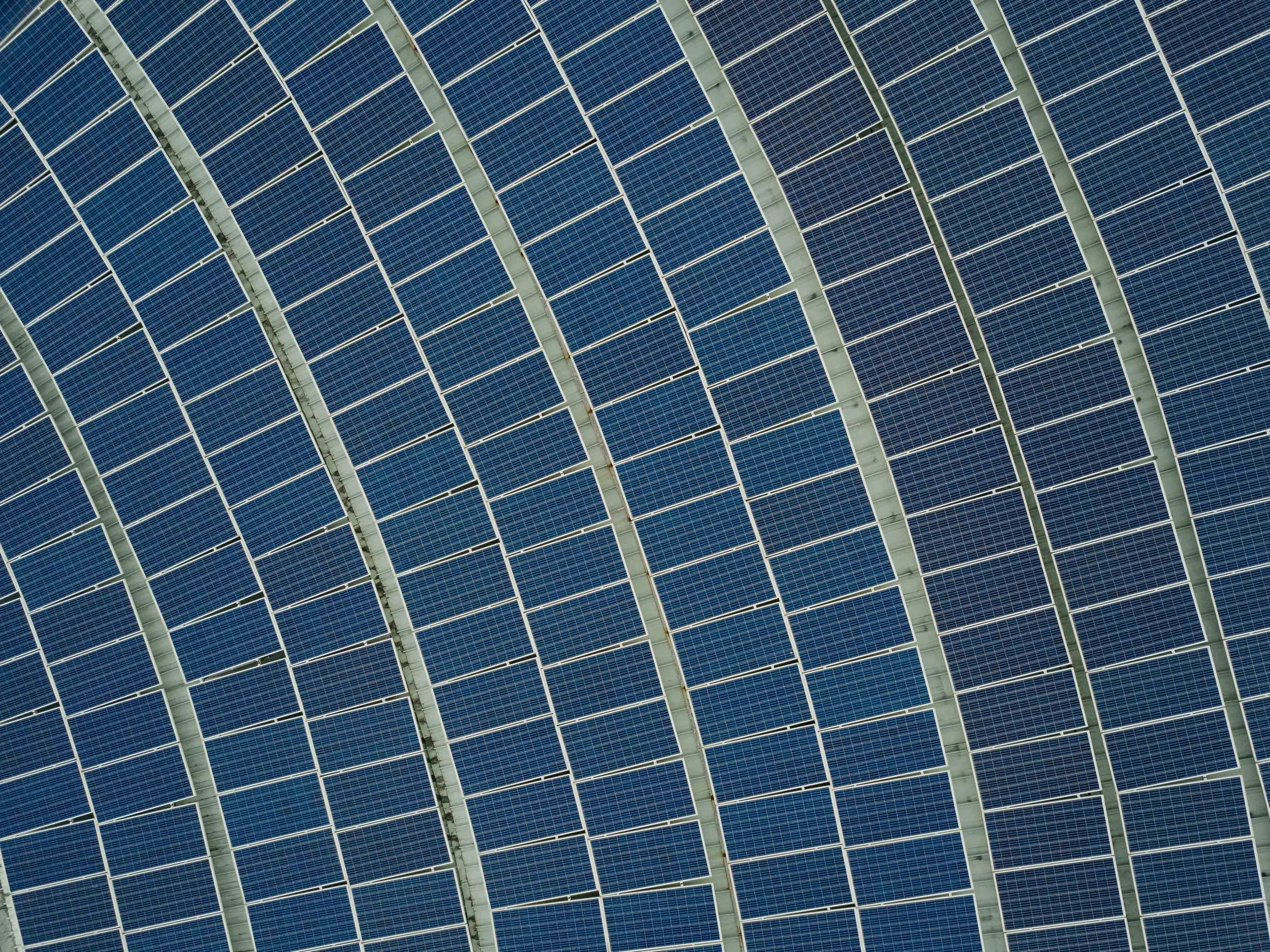 An aerial view of a large array of solar panels arranged in a grid pattern on a solar farm.