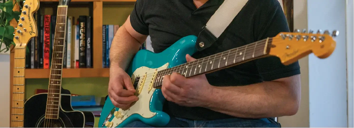 Close-up of a person playing an electric guitar focusing on the hands and fretboard