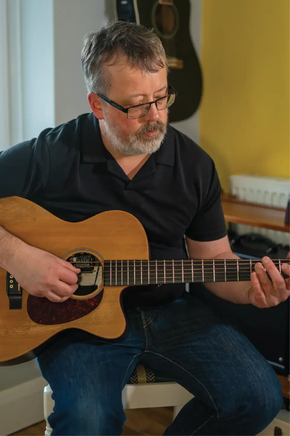 Guitar instructor playing an acoustic guitar while demonstrating technique