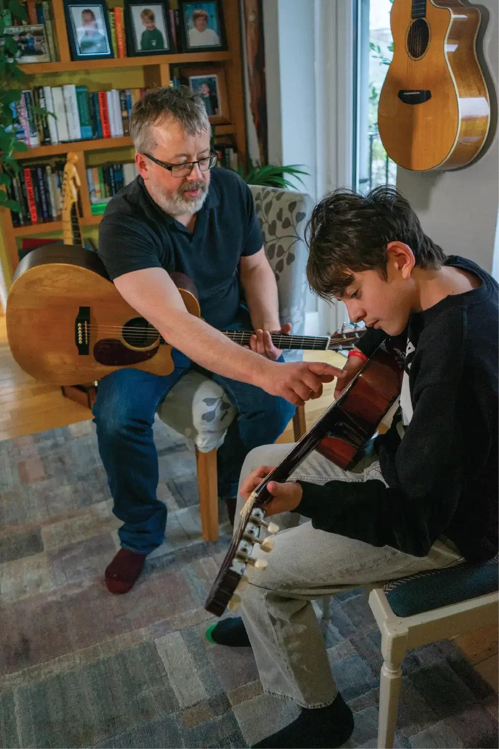 Guitar teacher guiding a student’s hand position on the guitar during a lesson