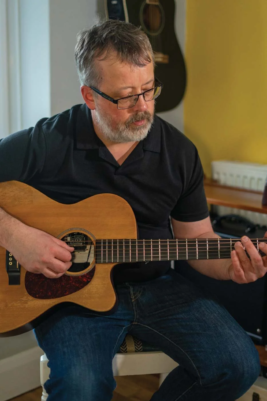 Guitar instructor playing an acoustic guitar while demonstrating technique