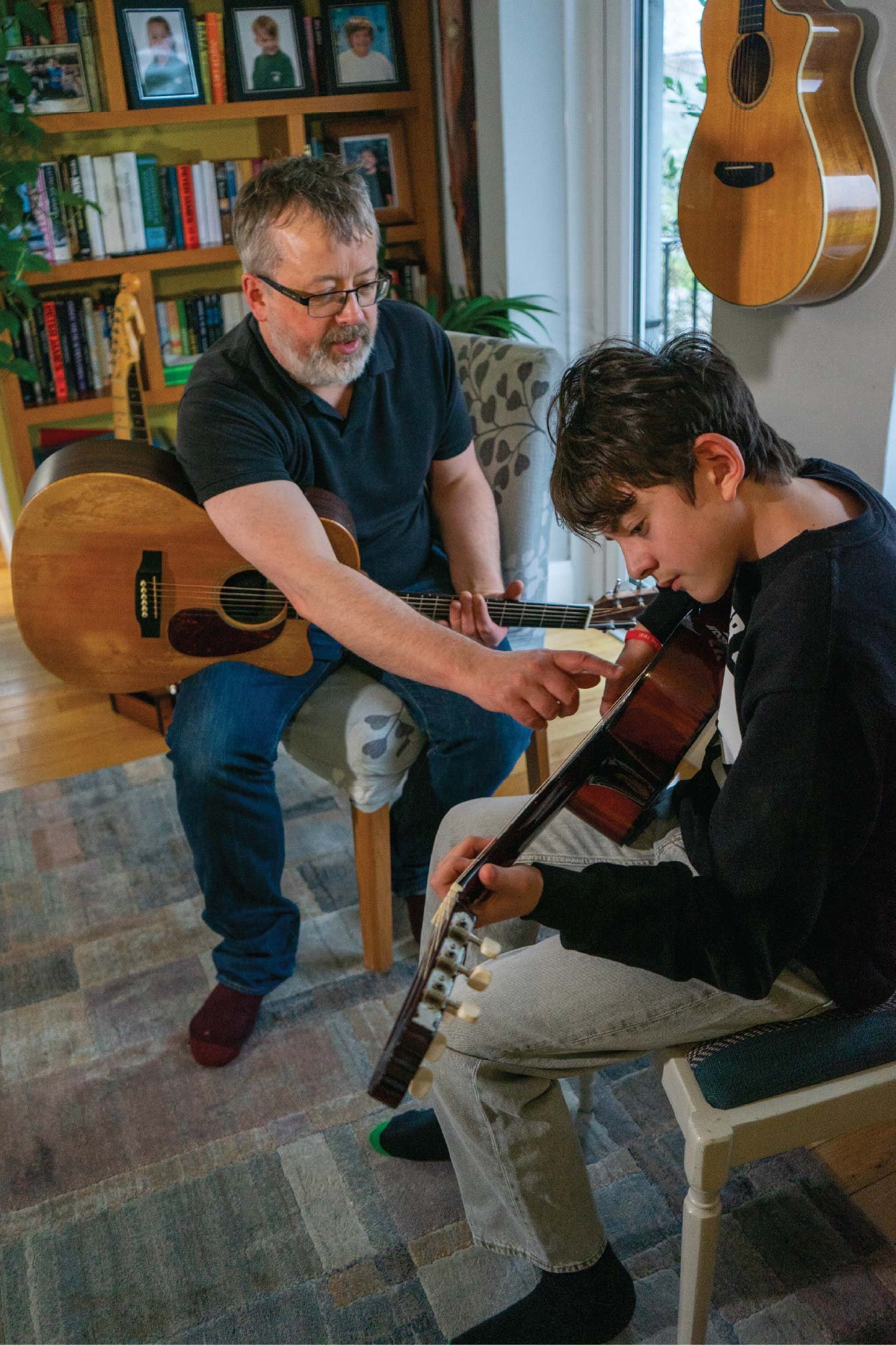 Guitar teacher guiding a student’s hand position on the guitar during a lesson