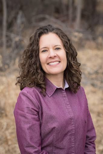 Heather with brown hair, smiling in a purple shirt.