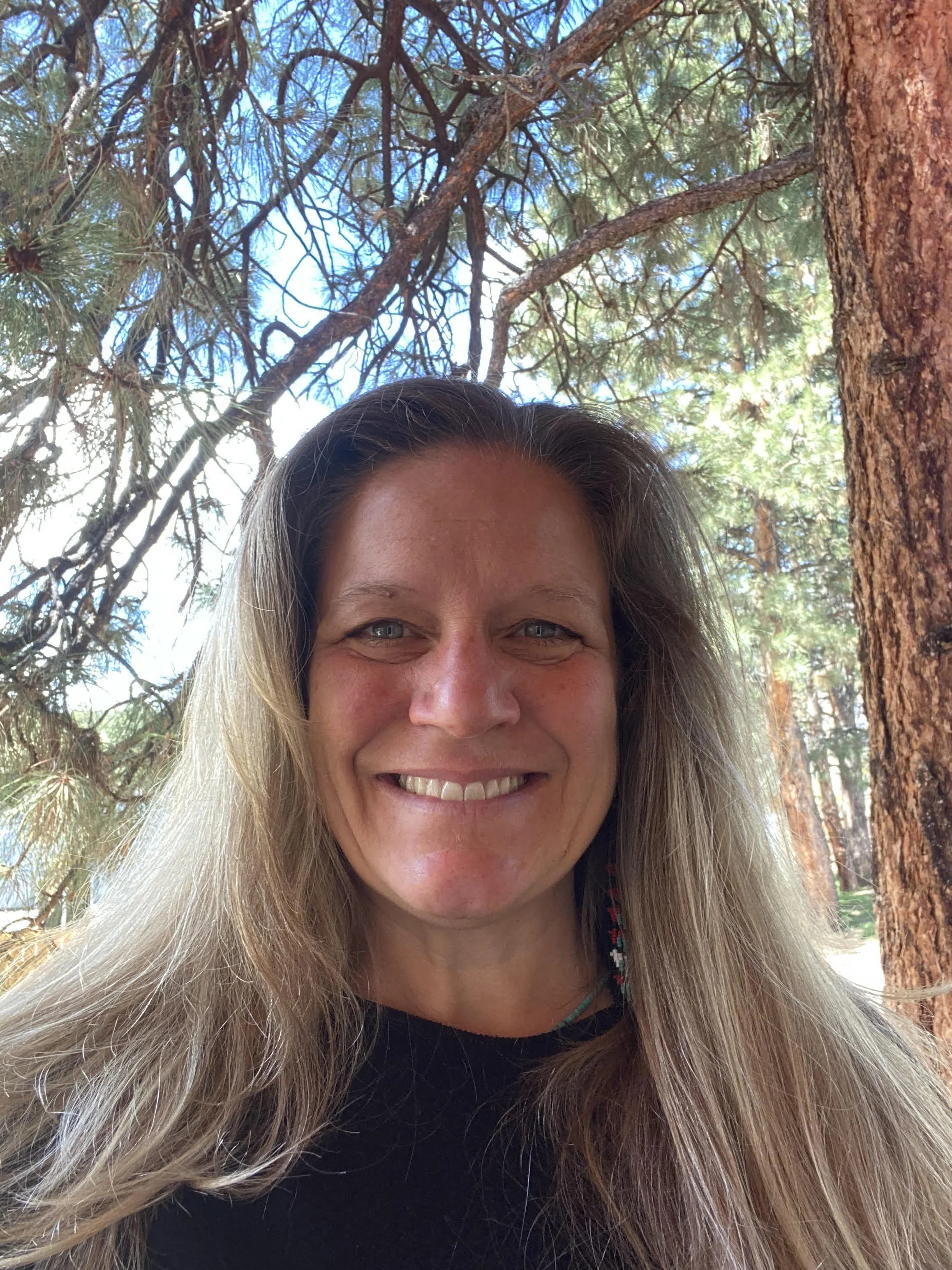 Stephanie with long light hair, smiling in a black shirt.