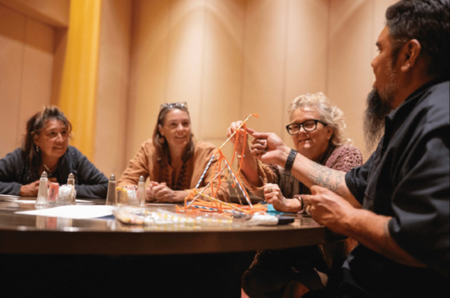 Four people sit around a round table engaged in a collaborative activity. 