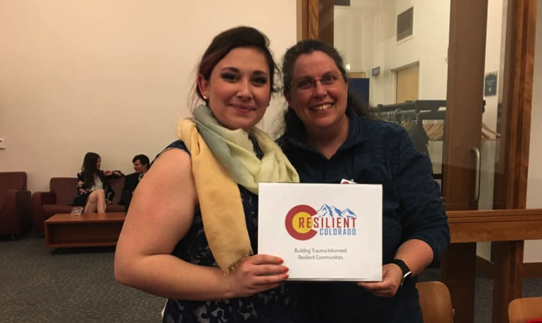 Doty and a community member are standing indoors, smiling at the camera.