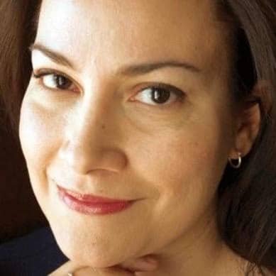 Close-up of a person with brown eyes and dark hair smiling softly.