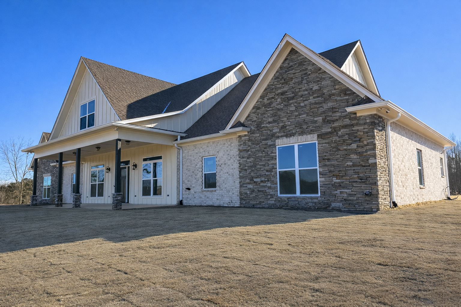 Custom-built modern farmhouse with stone and brick exterior by Alabama home builder New construction home with board and batten siding, stone facade, and covered porch