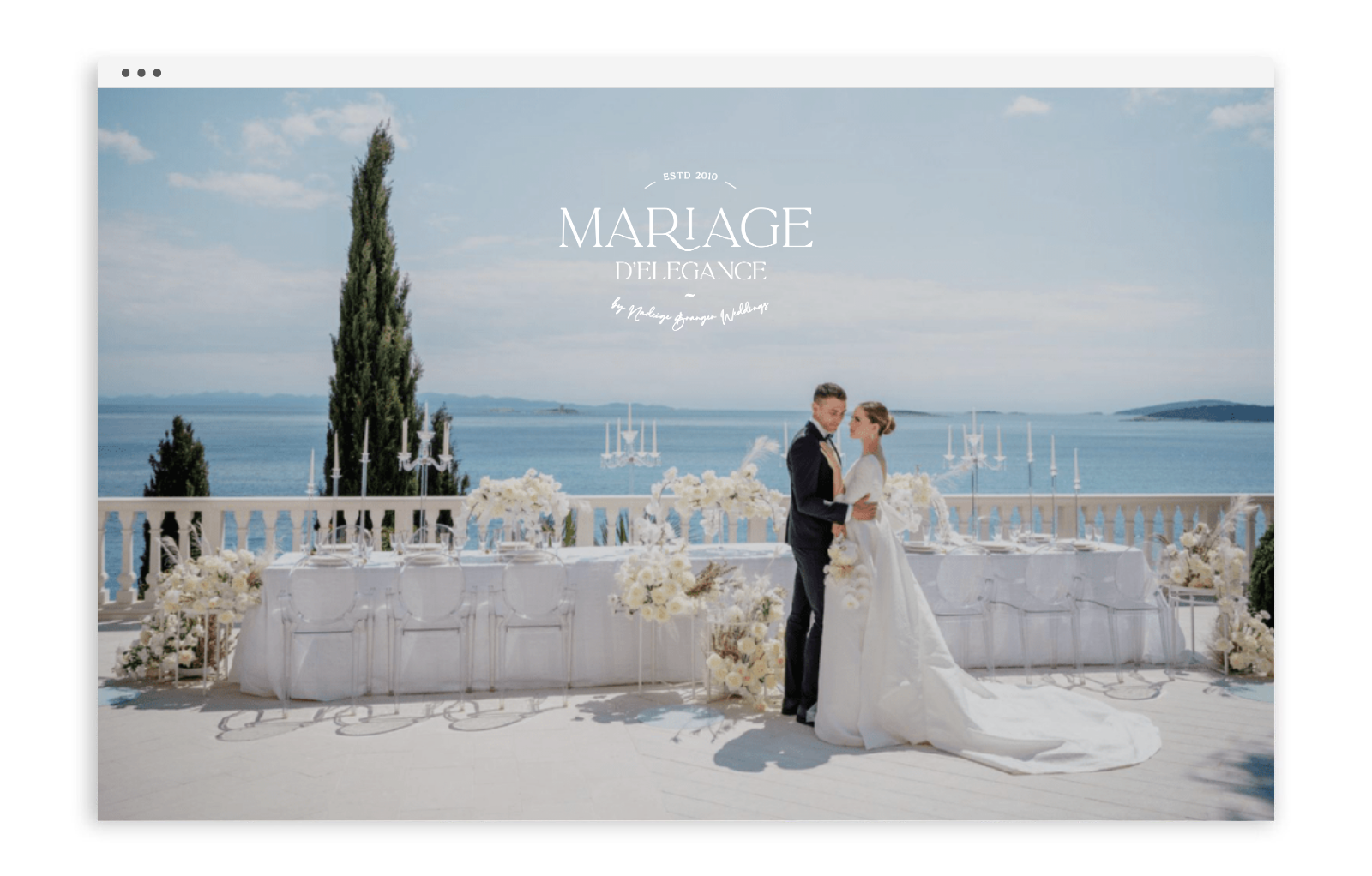 Un couple de mariés lors de leur mariage à l'extérieur avec vue sur la mer et un ciel bleu, décoré de fleurs blanches et d'une table élégante.