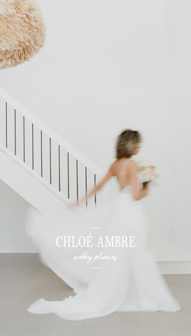 Une mariée en robe blanche marchant dans une maison moderne, tenant un bouquet.