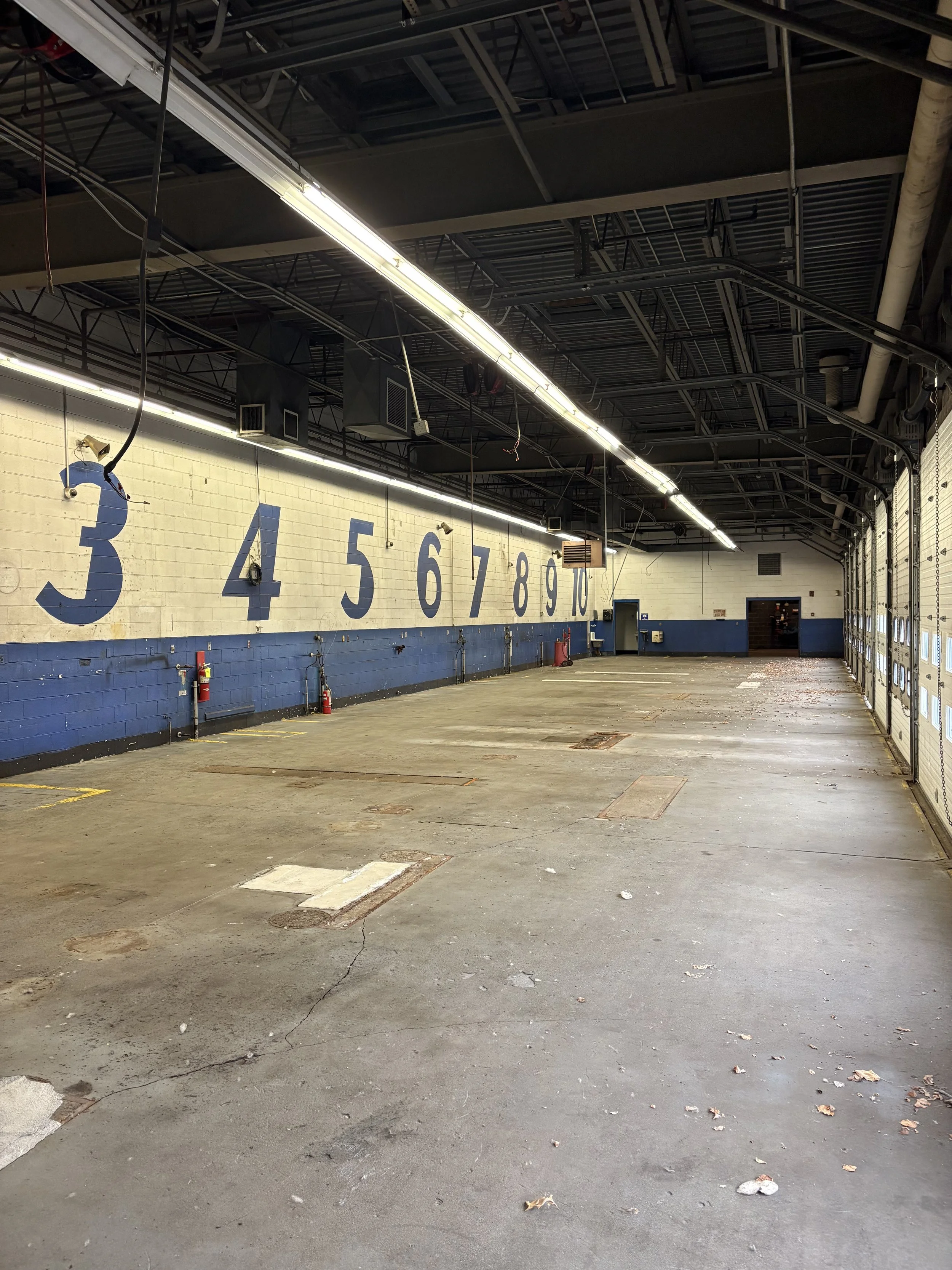 Empty garage or parking lot with large painted numbers 3 through 10 on the wall and garage doors on the right side.