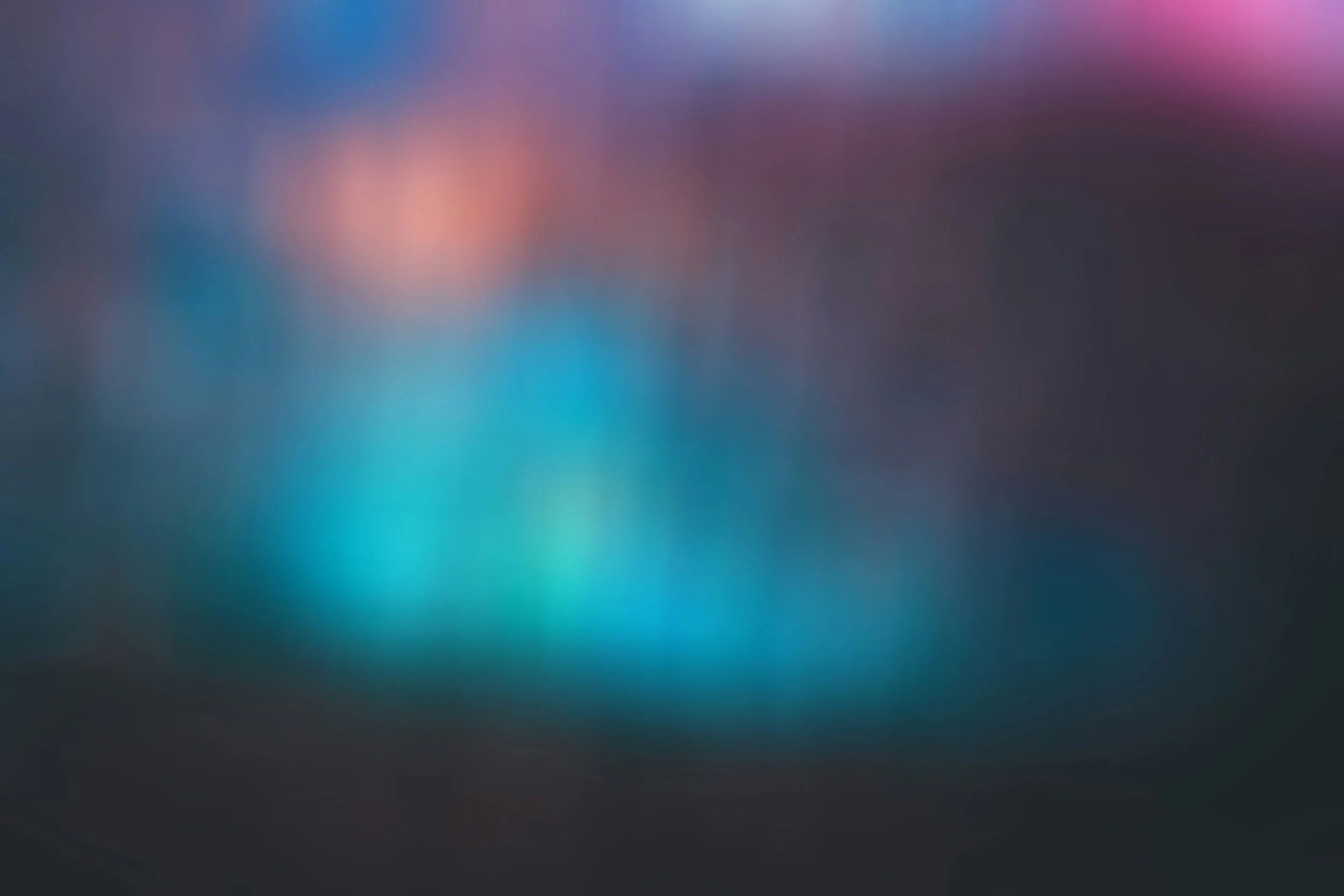 Blurred colorful lights with a mix of pink, blue, purple, and orange hues.