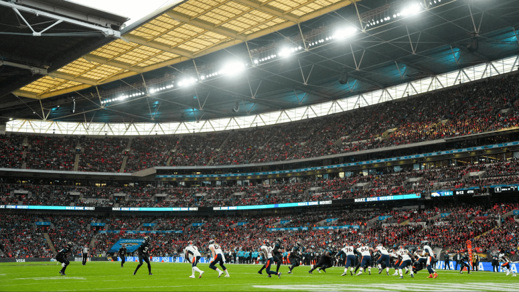 An American football game in a large stadium with players on the field and fans in the stands.
