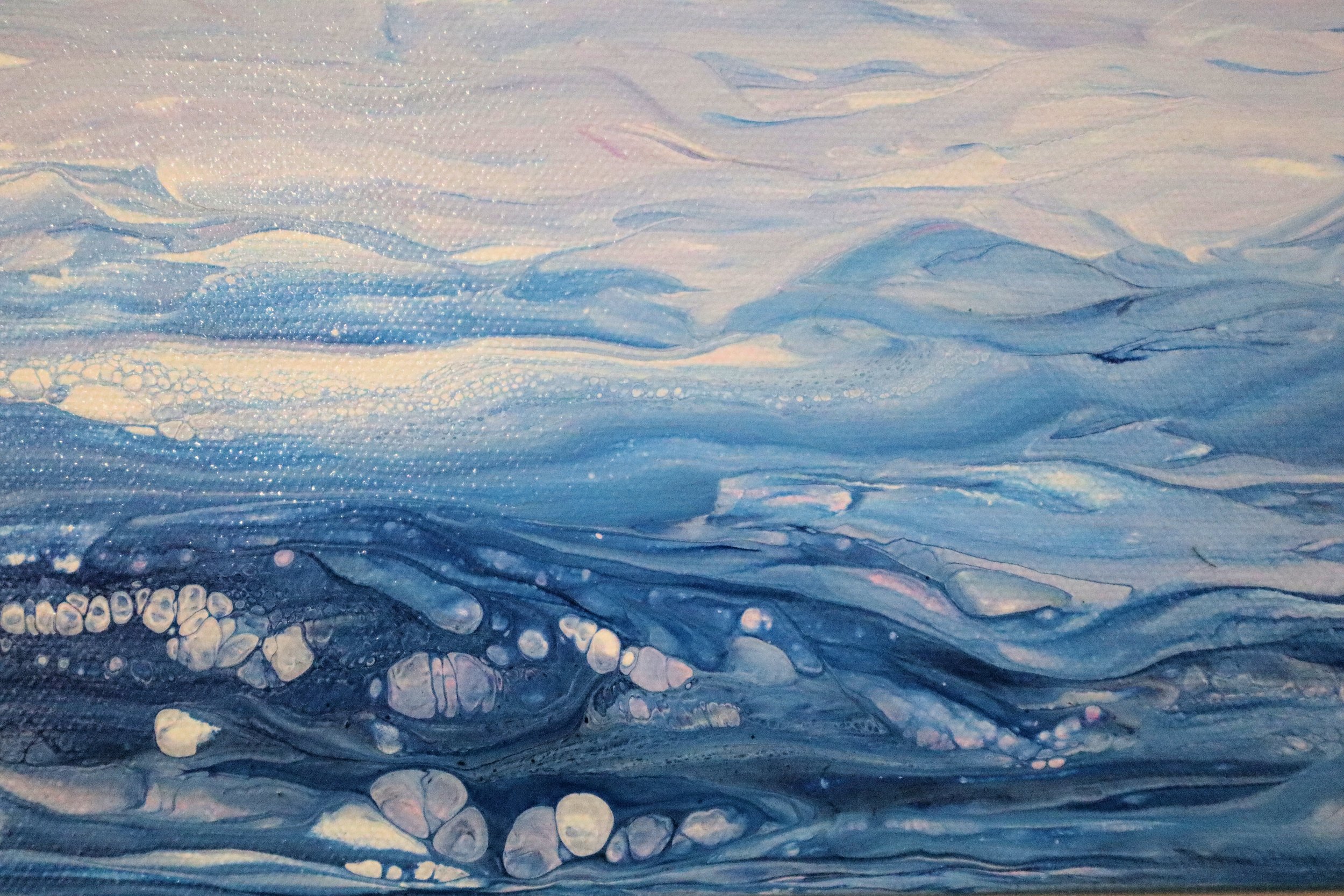 A close-up of an abstract watercolor painting with layers of blue, white, and pastel shades blending and flowing together.