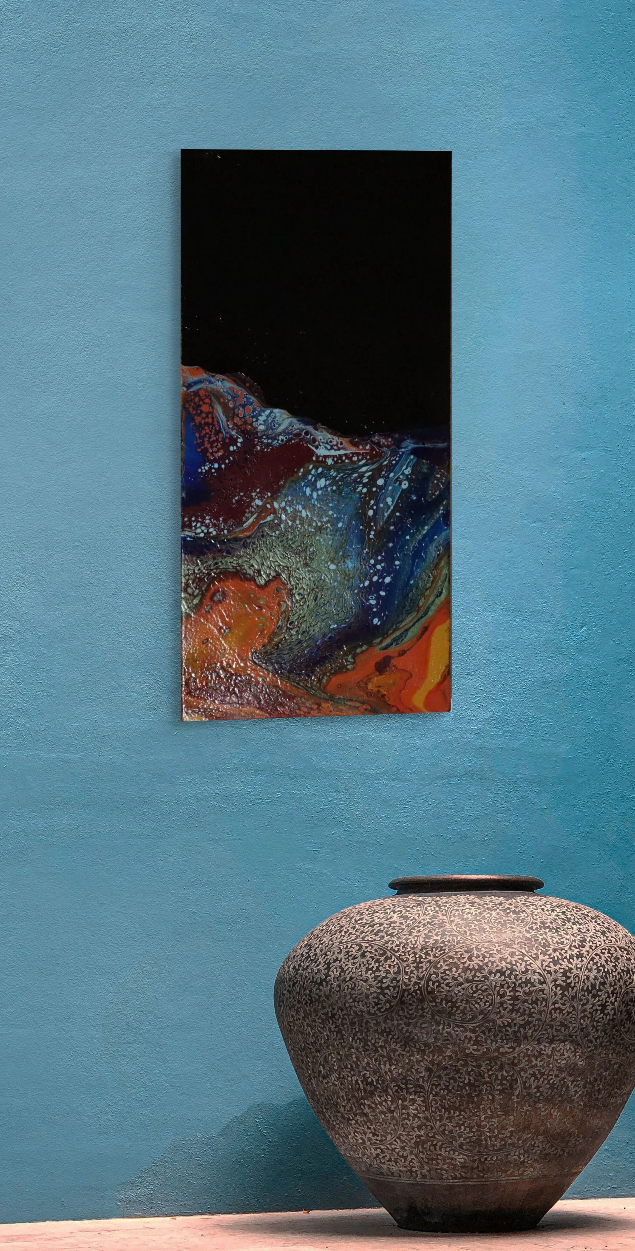 A colorful abstract painting hangs on a blue wall above a large, ornate decorative vase on a wooden floor.