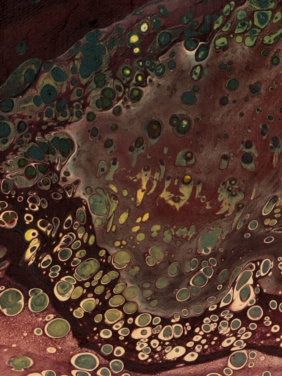 Close-up of a colorful abstract pattern with various circular shapes and bubbles, primarily in green, yellow, and brown tones.