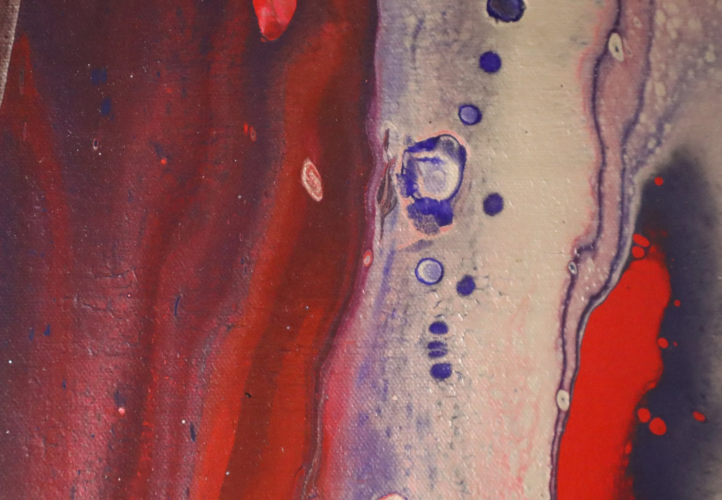 Close-up view of an abstract colorful painting with red, purple, and beige hues, featuring various textures and circular patterns.