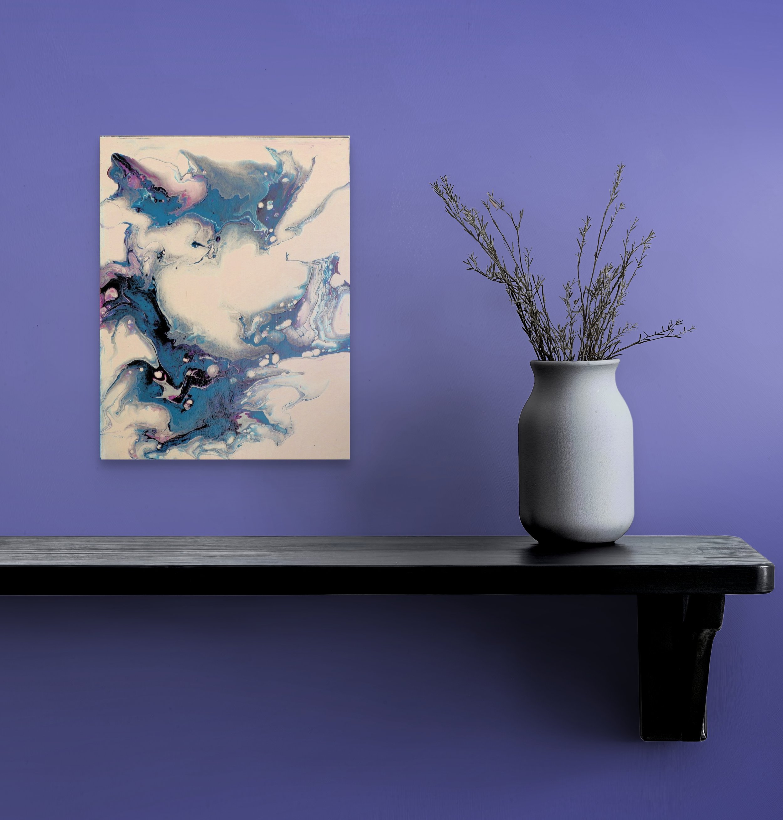A blue and white abstract painting hangs on a purple wall. To the right, there is a gray vase with leafy green plant branches placed on a dark table.