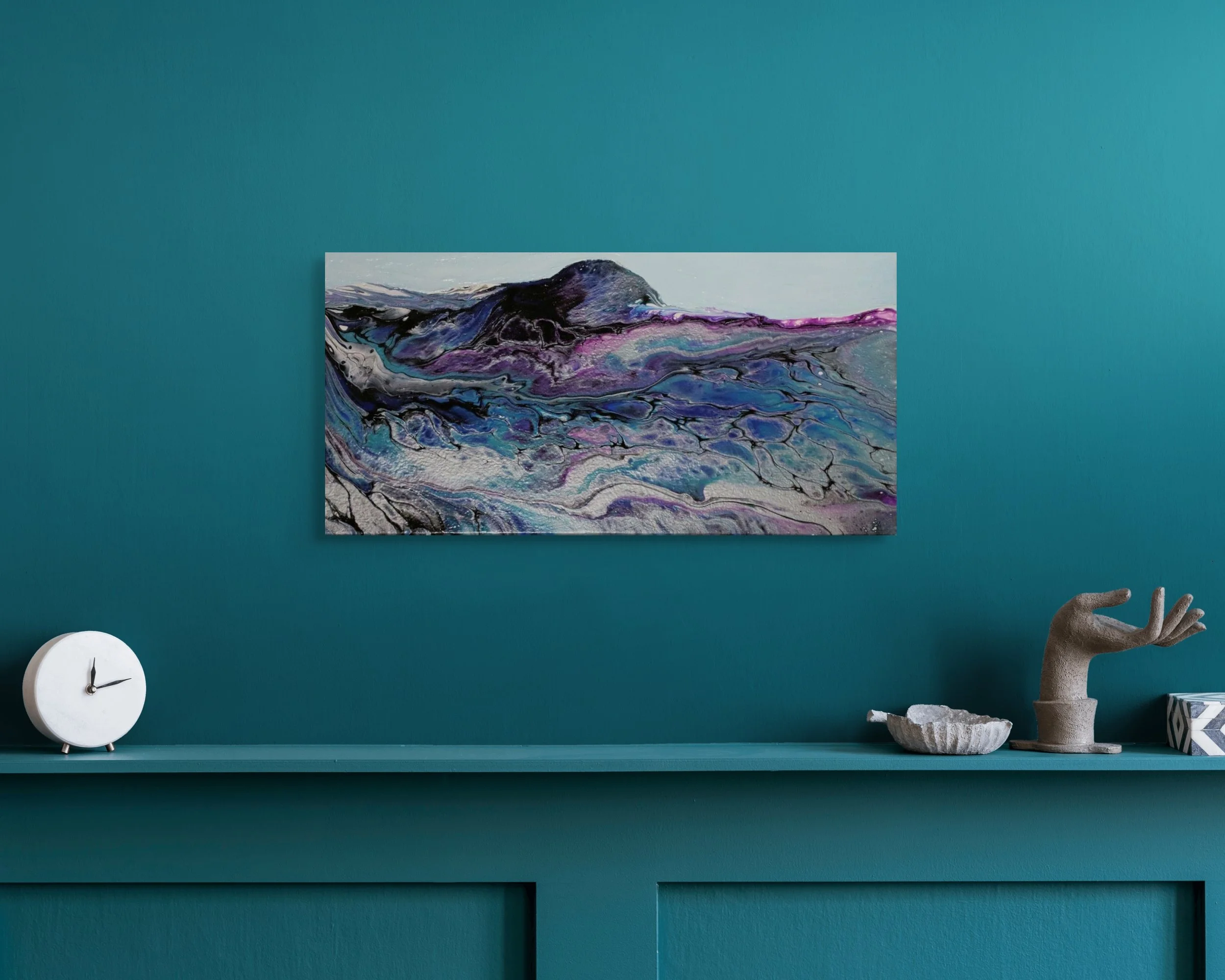 Room with teal wall, abstract painting, white clock, sculpture of a hand and rocks, and small decorative objects on a teal shelf.