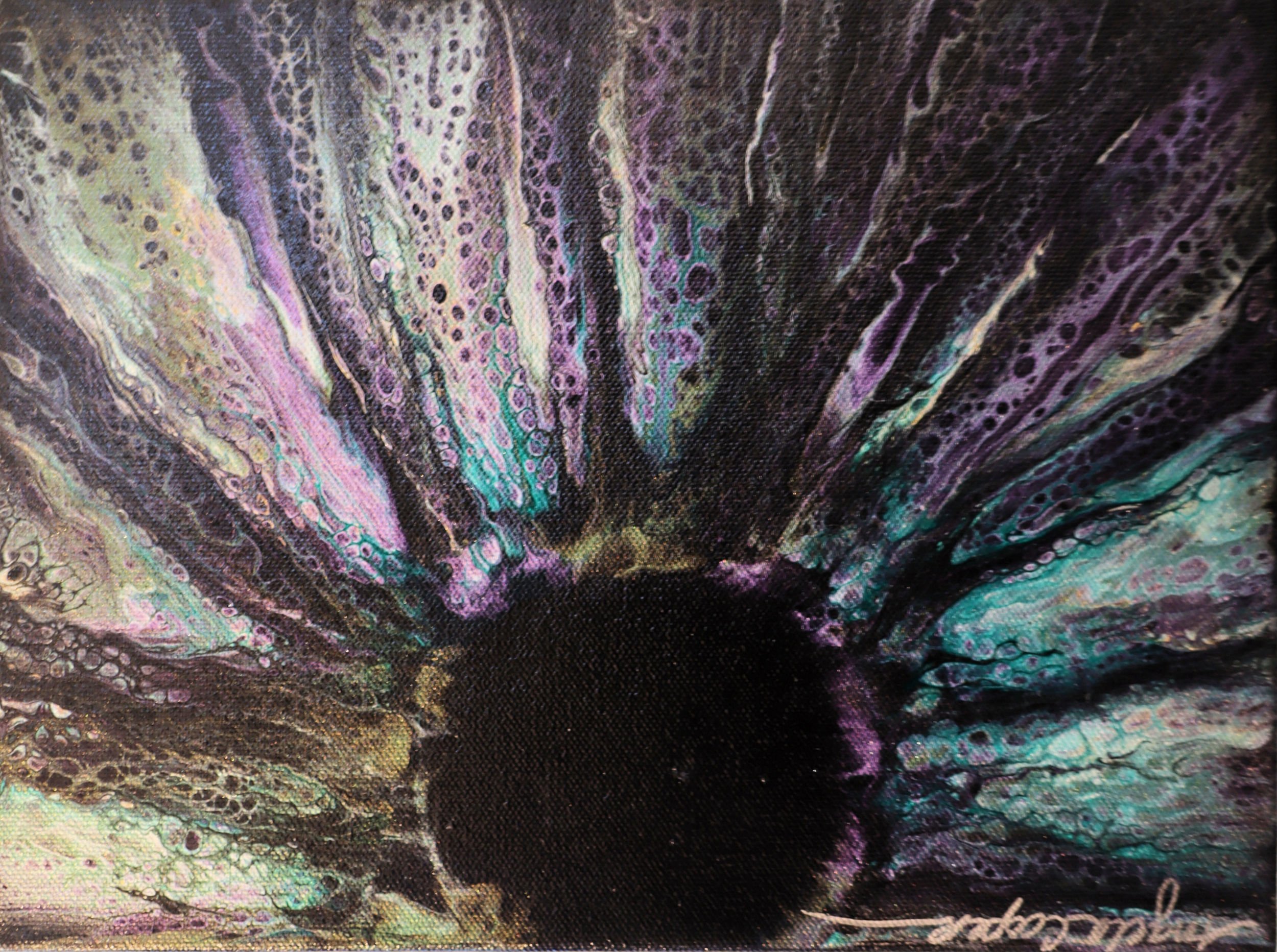 Close-up image of a colorful, abstract, or oil paint pattern with various flowing lines and spots in iridescent shades of purple, green, yellow, and black.