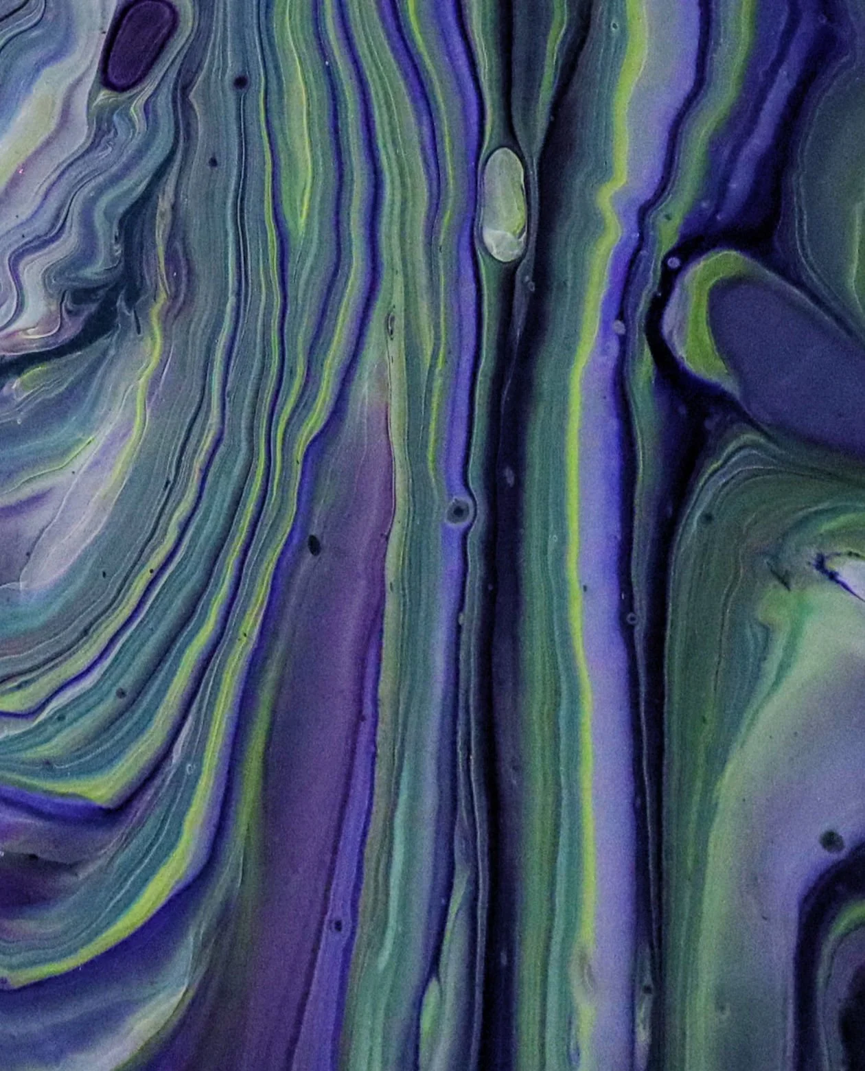 Close-up of an abstract fluid art painting with swirls of purple, green, blue, and yellow.