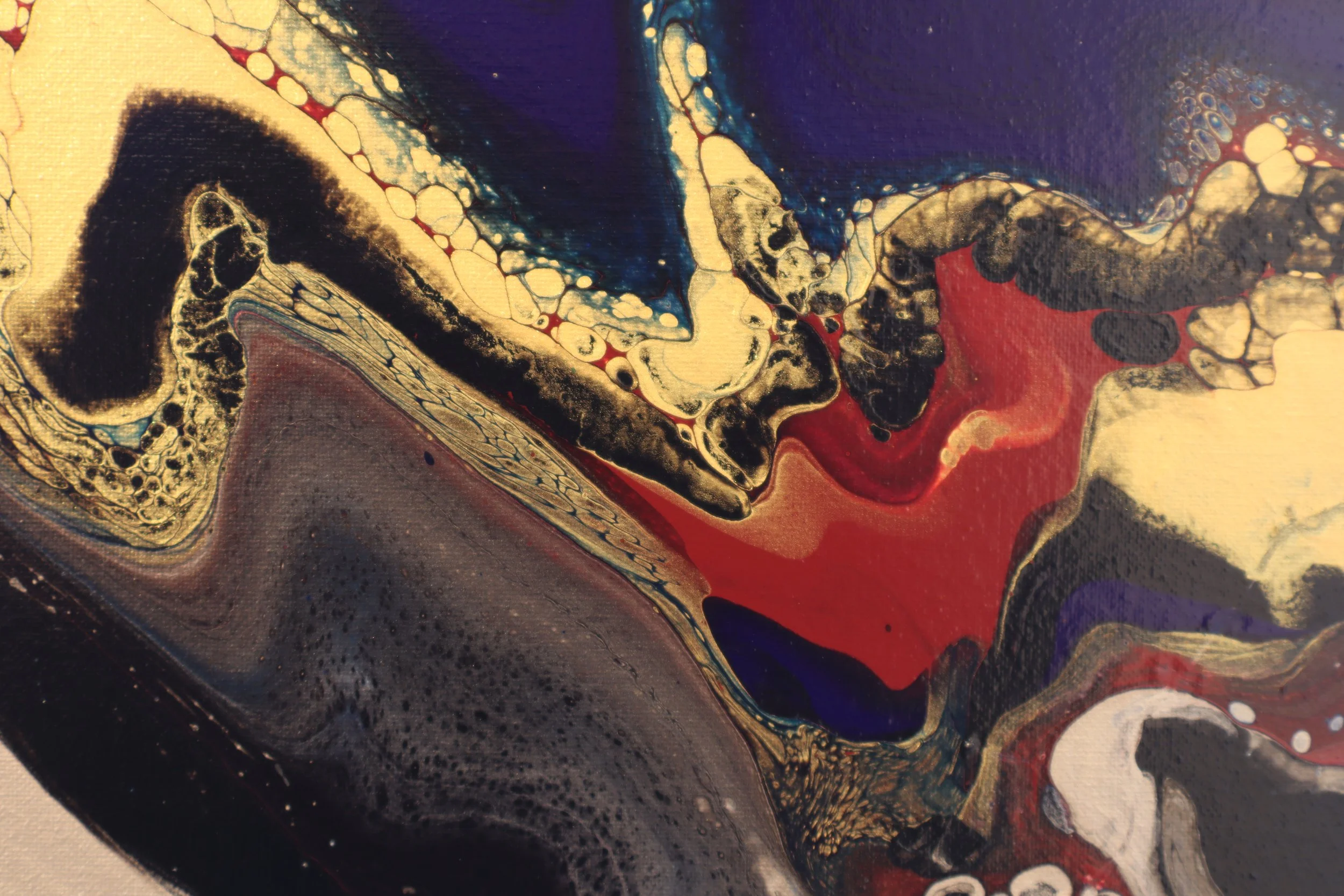 Close-up of an abstract painting with swirling patterns in black, gold, red, blue, and white, resembling a cosmic or geological scene.