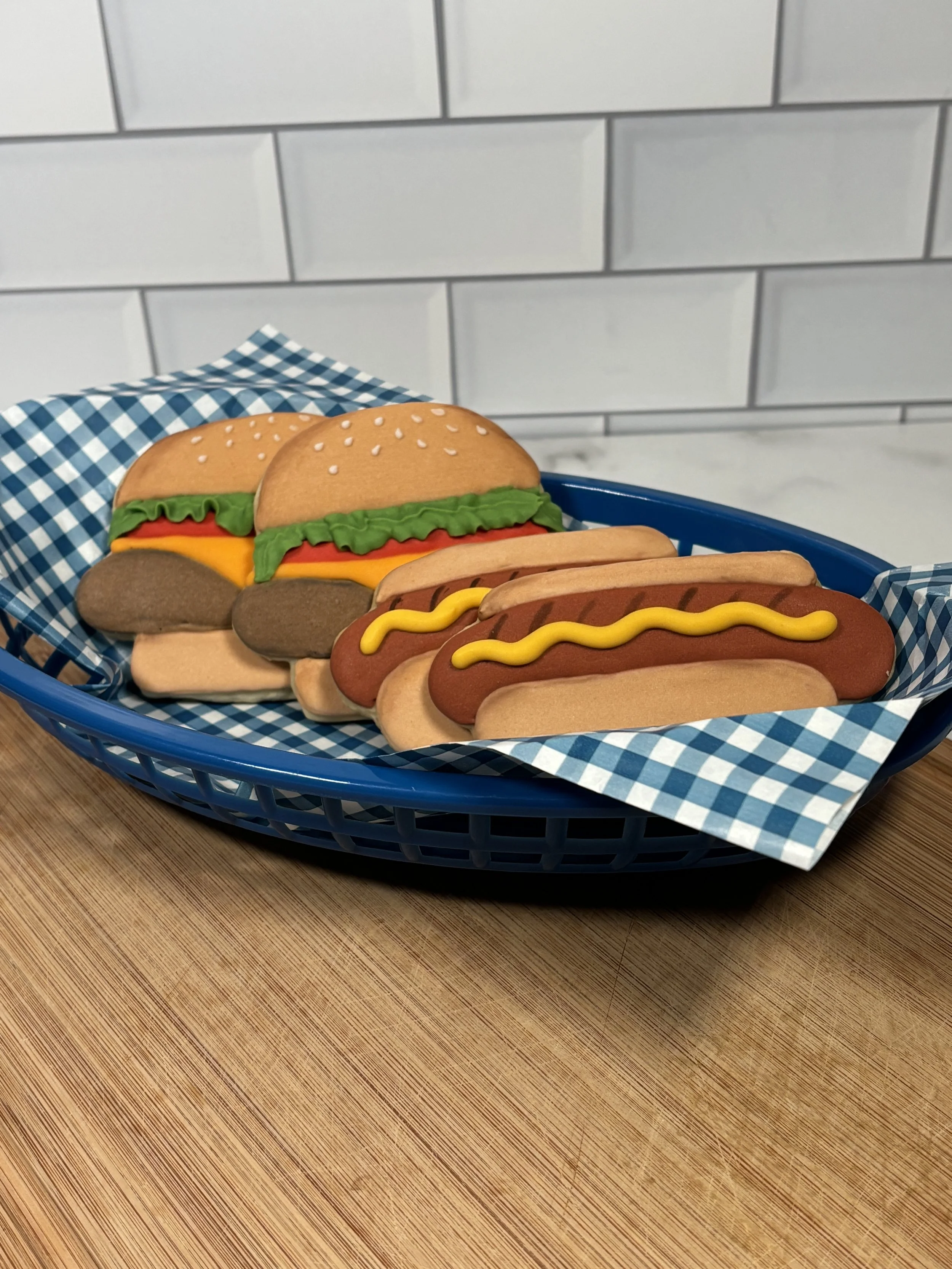 Decorated cookies shaped like burgers, hot dogs, and sandwiches from Mary's Bakehouse