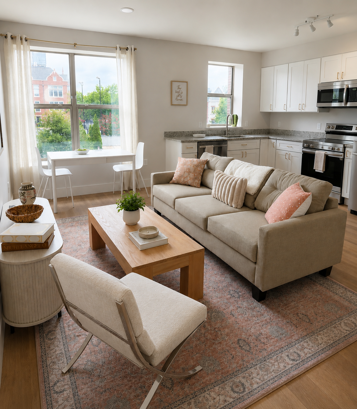 Open-concept living room and kitchen with beige sofa, patterned pillows, wooden coffee table, white dining table with chairs, large windows with curtains, and stainless steel appliances.