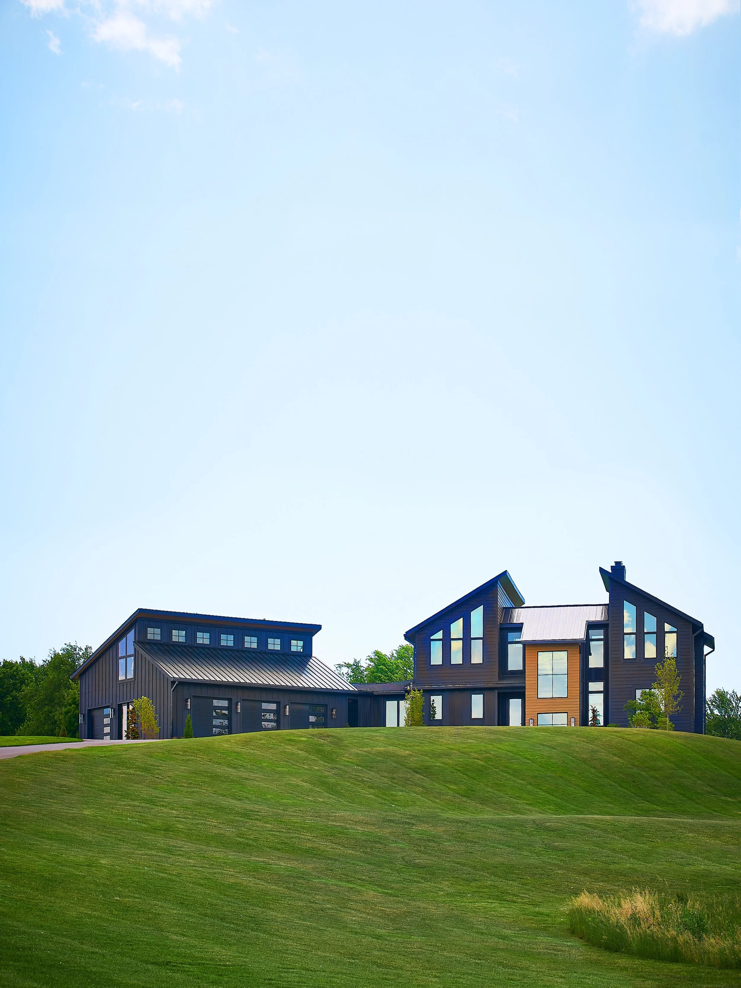 When a client needs space for four cars and wants a home that feels like it belongs to the landscape, proportion becomes the whole problem. A 1,360-square-foot garage beside roughly 3,500 square feet of living space can easily take over the fa&ccedil