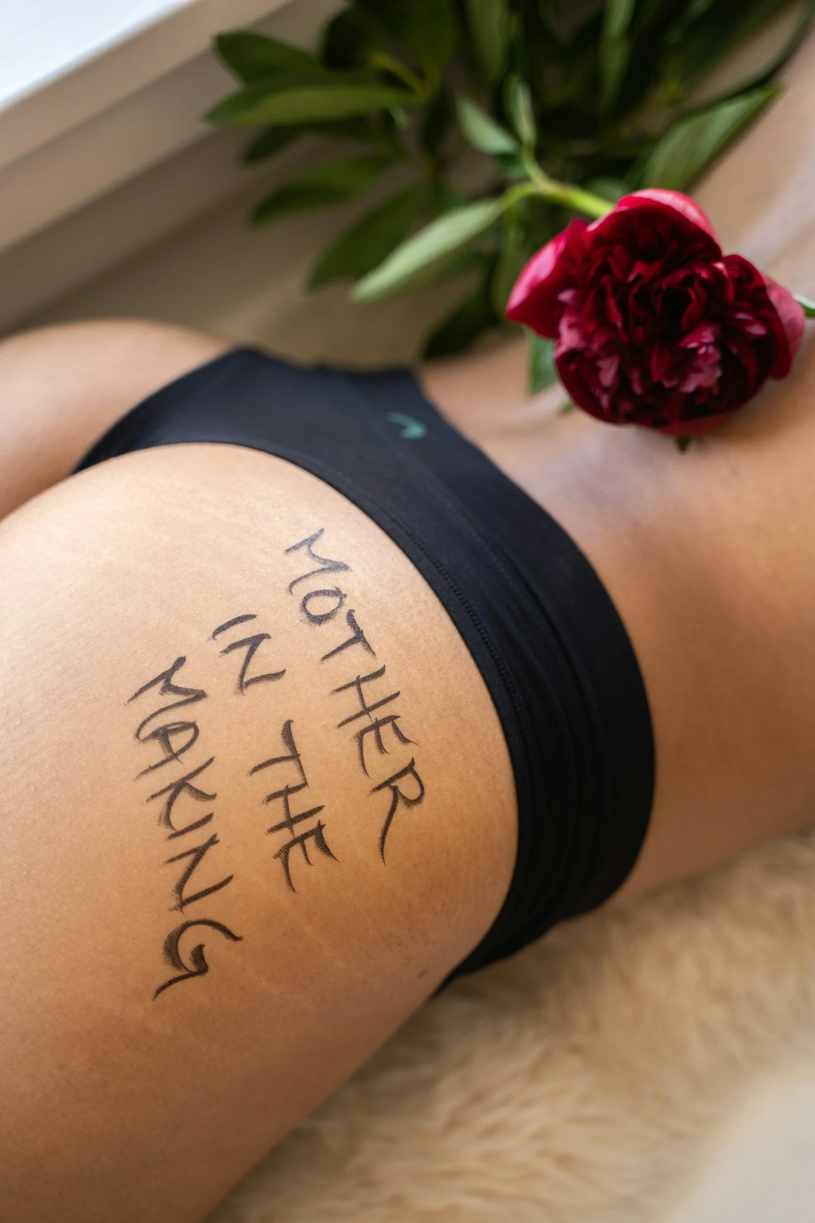 Close-up of a person's thigh with handwritten text and a red flower.