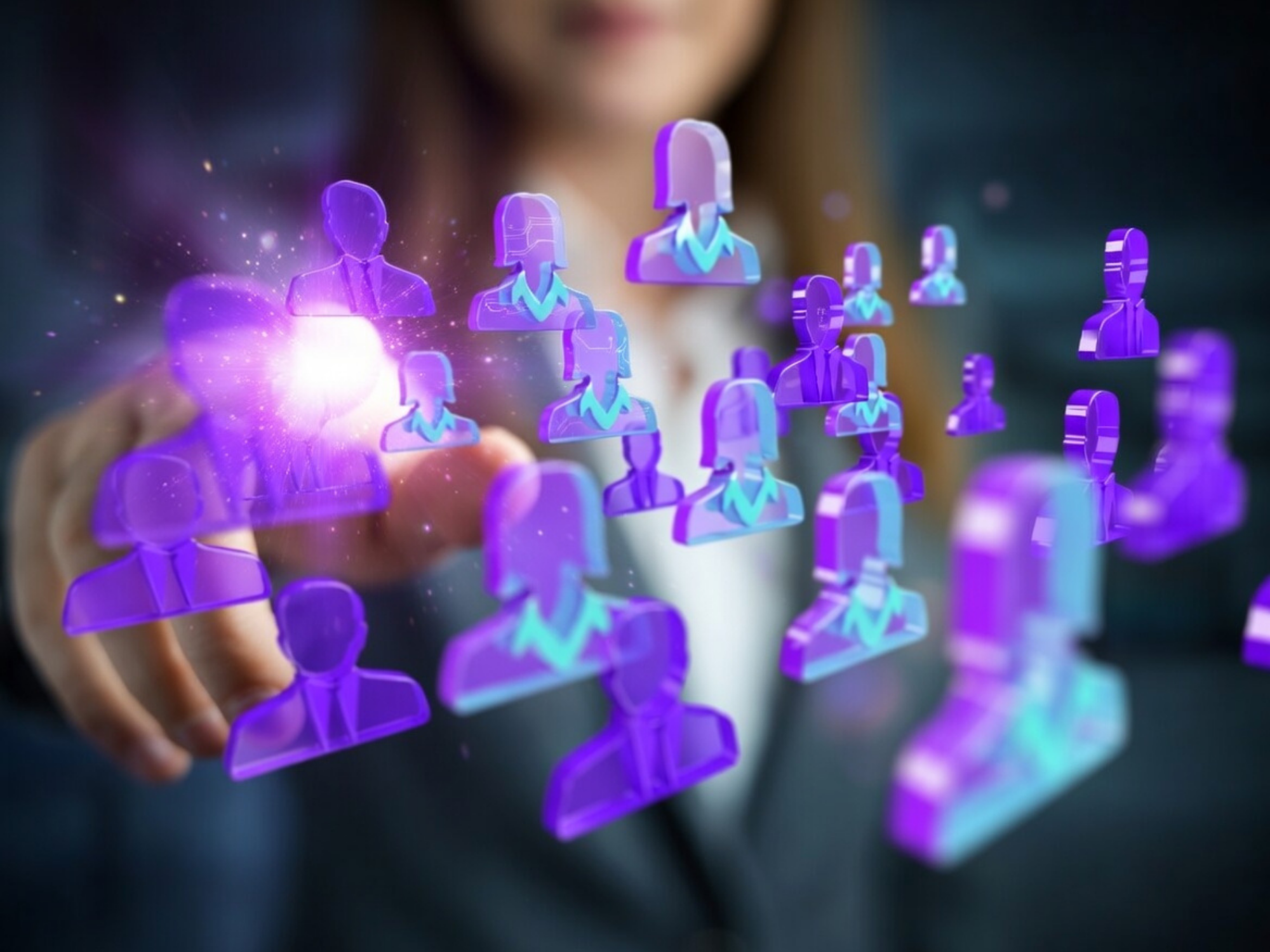 Person in business attire interacting with a holographic display of purple human icons representing a social network that would be provided by Emori Staffing Solutions.