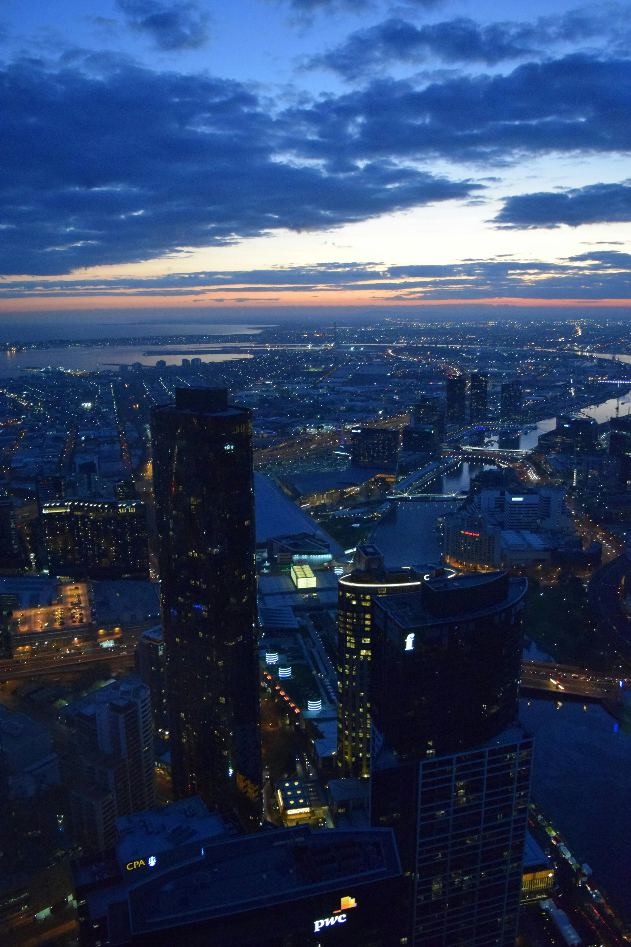 Nighttime cityscape with illuminated skyscrapers, bridges, and a river under a partly cloudy sky where people would need staffing opportunities.