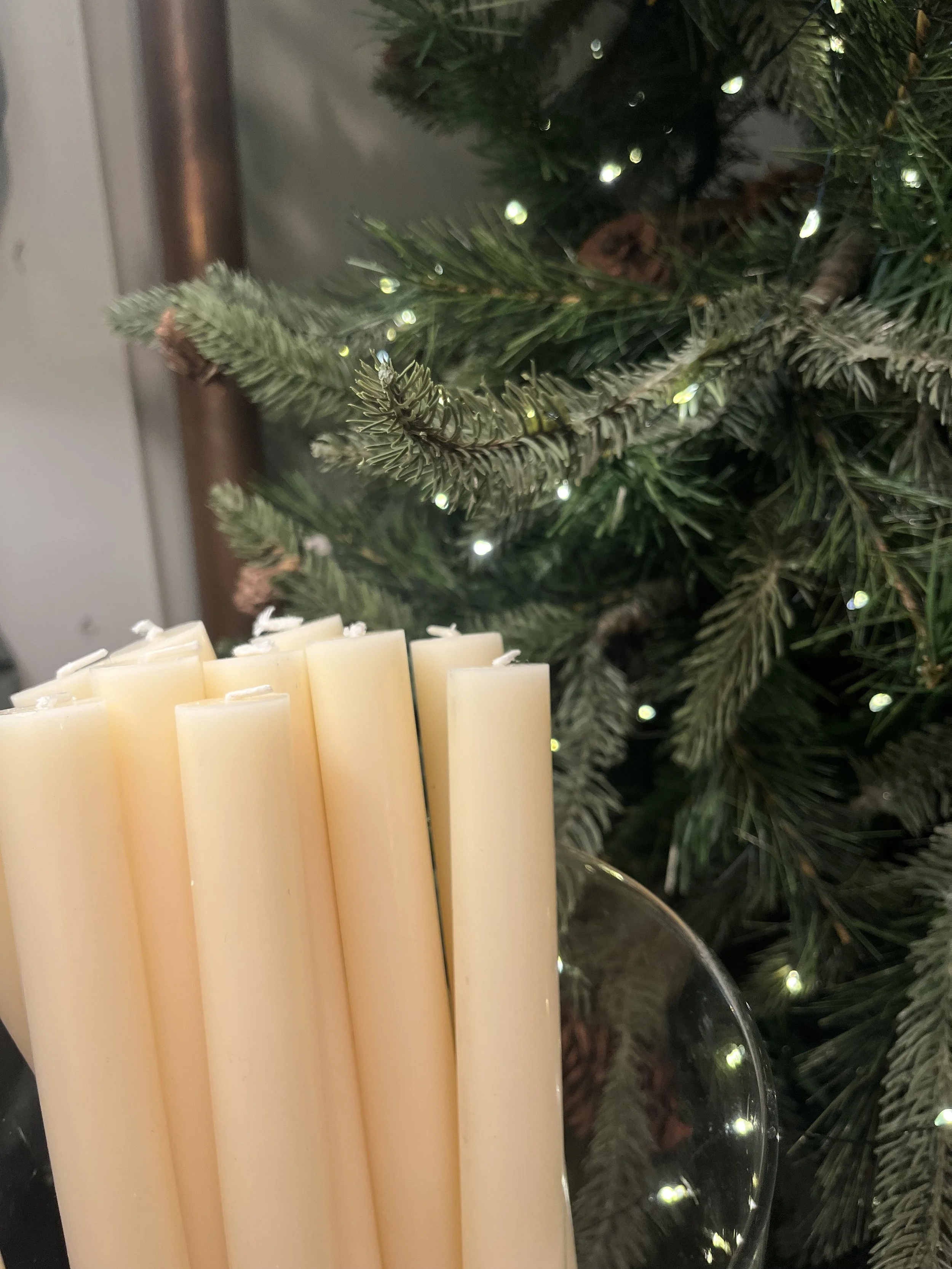 Close-up of white candles with a decorated Christmas tree in the background.