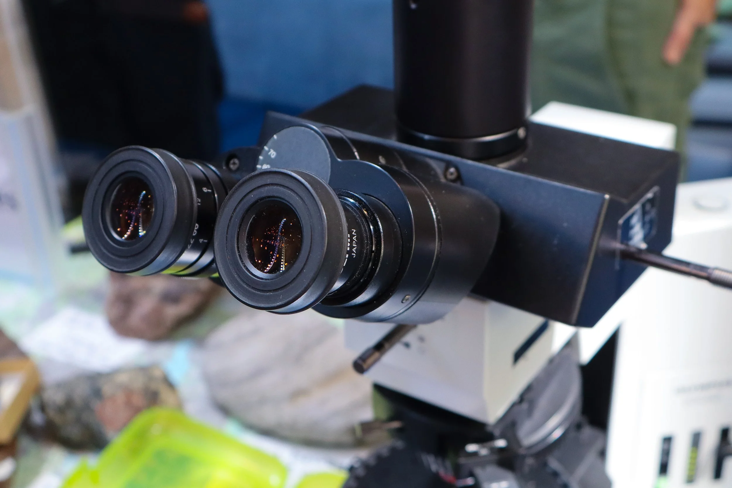 Close-up of a microscope with dual eyepieces, focusing on the optical components.