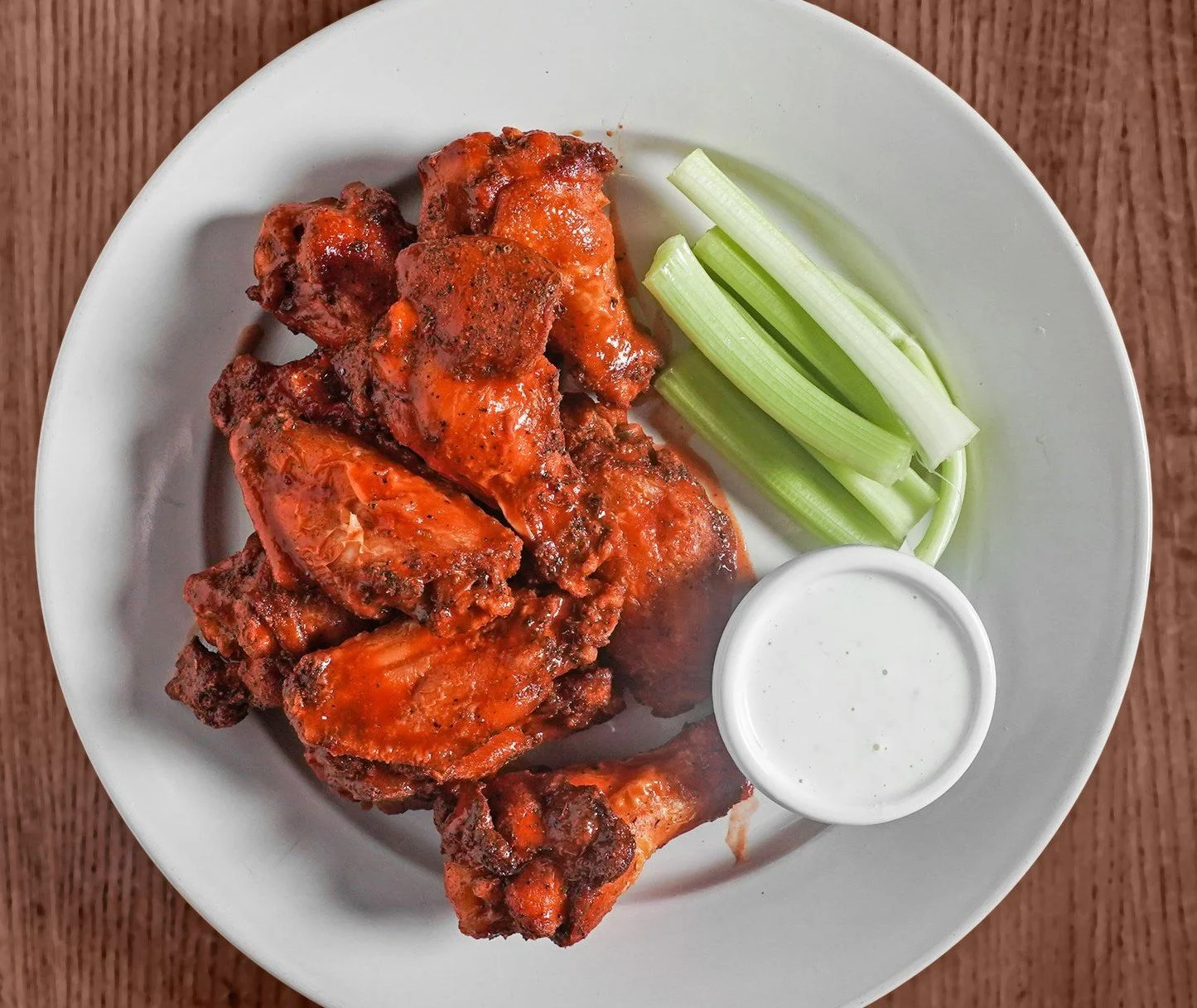 Plate of barbecue chicken with a side of celery sticks and ranch dipping sauce.