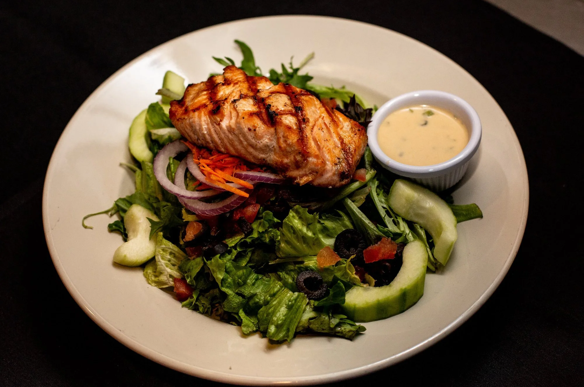 Tavern Salad with grilled salmon, mixed greens, cucumber, red onion, carrot and black olives at Windward Tavern in Alpharetta, Georgia