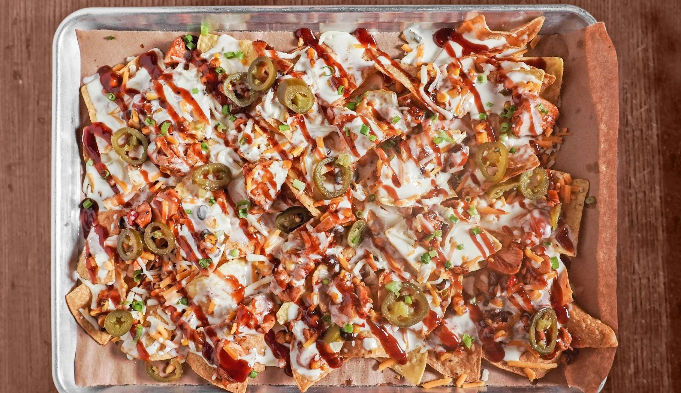 Corn tortilla chips layered with pulled chicken, house made BBQ sauce, queso and pickled jalapenos. Built to share at Windward Tavern in Alpharetta, GA.