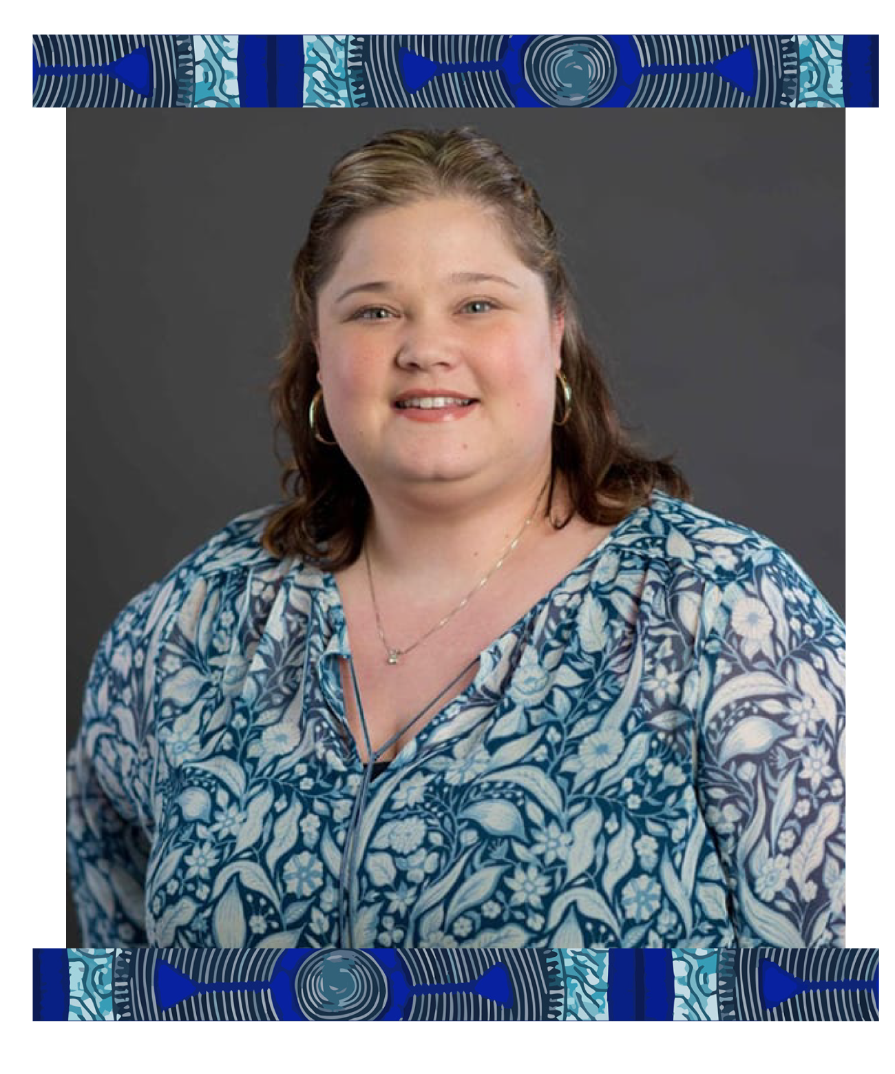 A woman with shoulder-length brown hair, wearing a blue and white floral patterned blouse, gold hoop earrings, a gold necklace, and a blue lanyard, smiling at the camera against a gray background with decorative blue and black borders at the top and bottom.