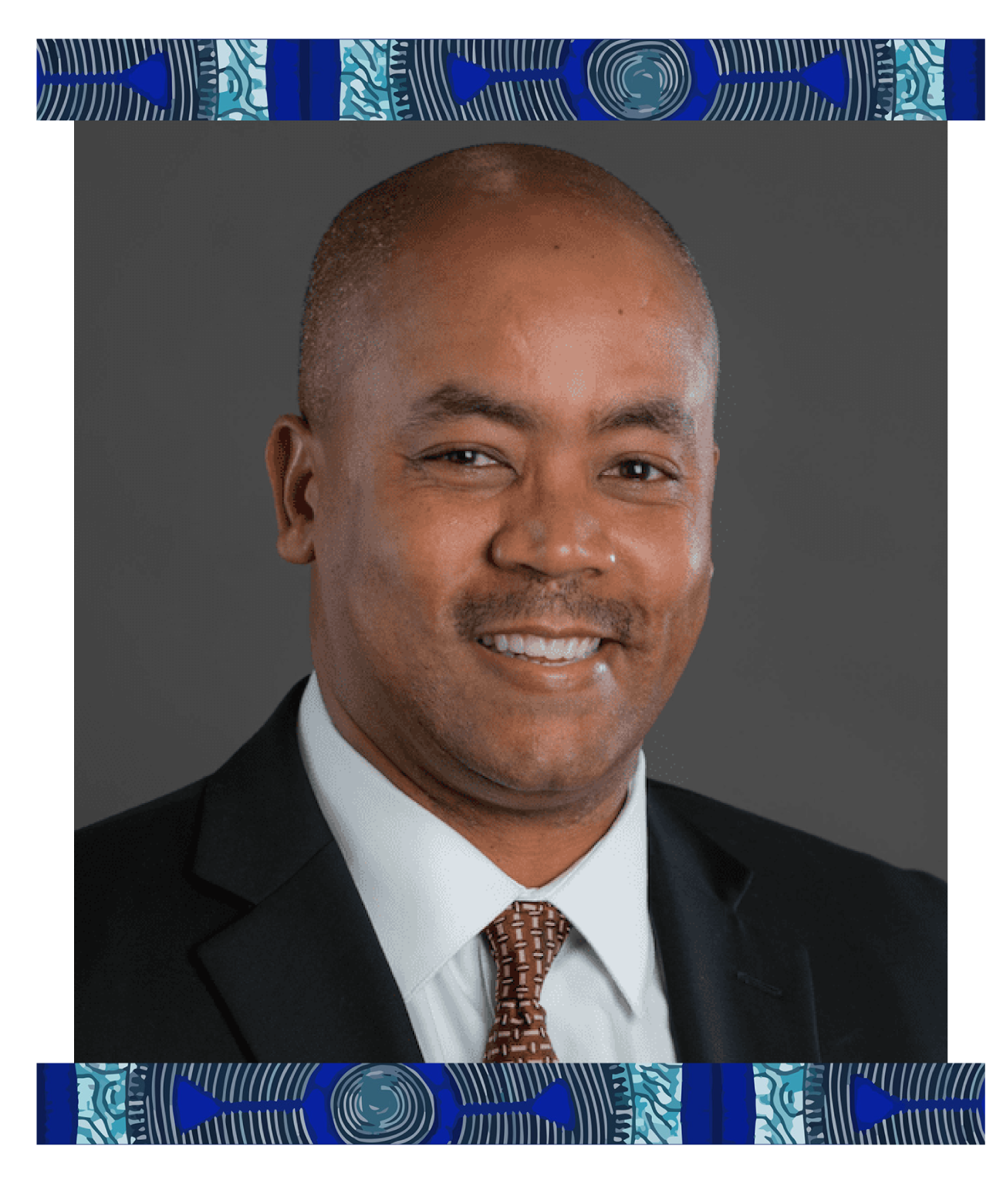 Headshot of an African American man in a suit, smiling, with a dark gray background and a decorative patterned border at the top and bottom.